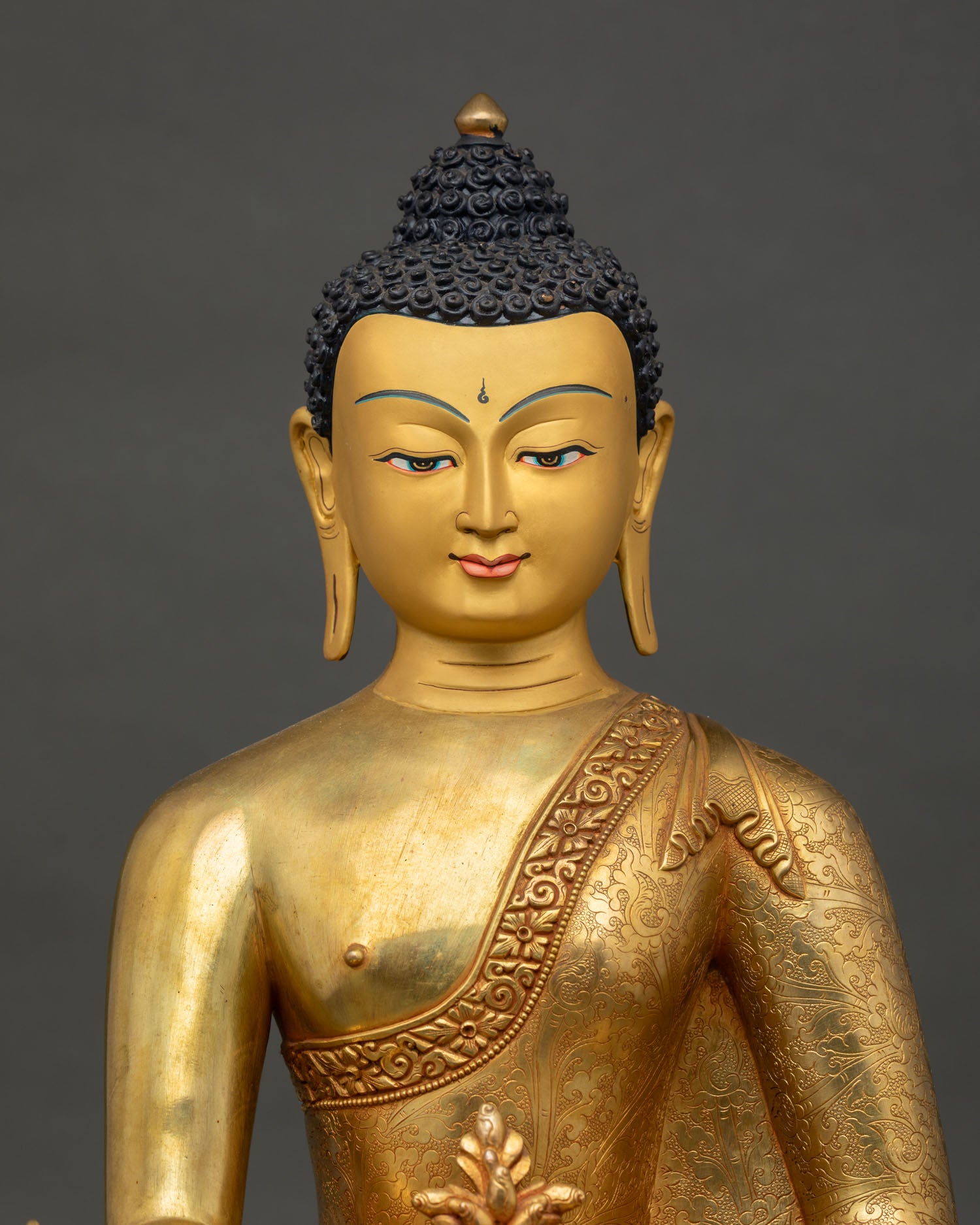 close-up of handcrafted medicine buddha statue with fire-gilded copper details