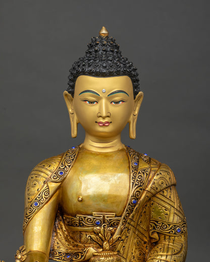 Close up of handmade Medicine Buddha statue with gold fire-gilded robe and semi-precious stone inlays