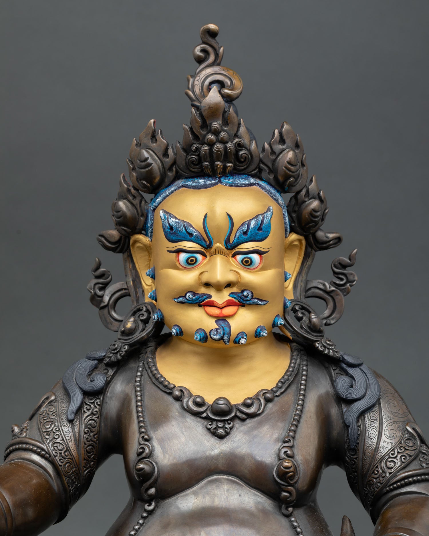 Close up of Jambhala statue with gold painted face and intricate Nepalese craftsmanship