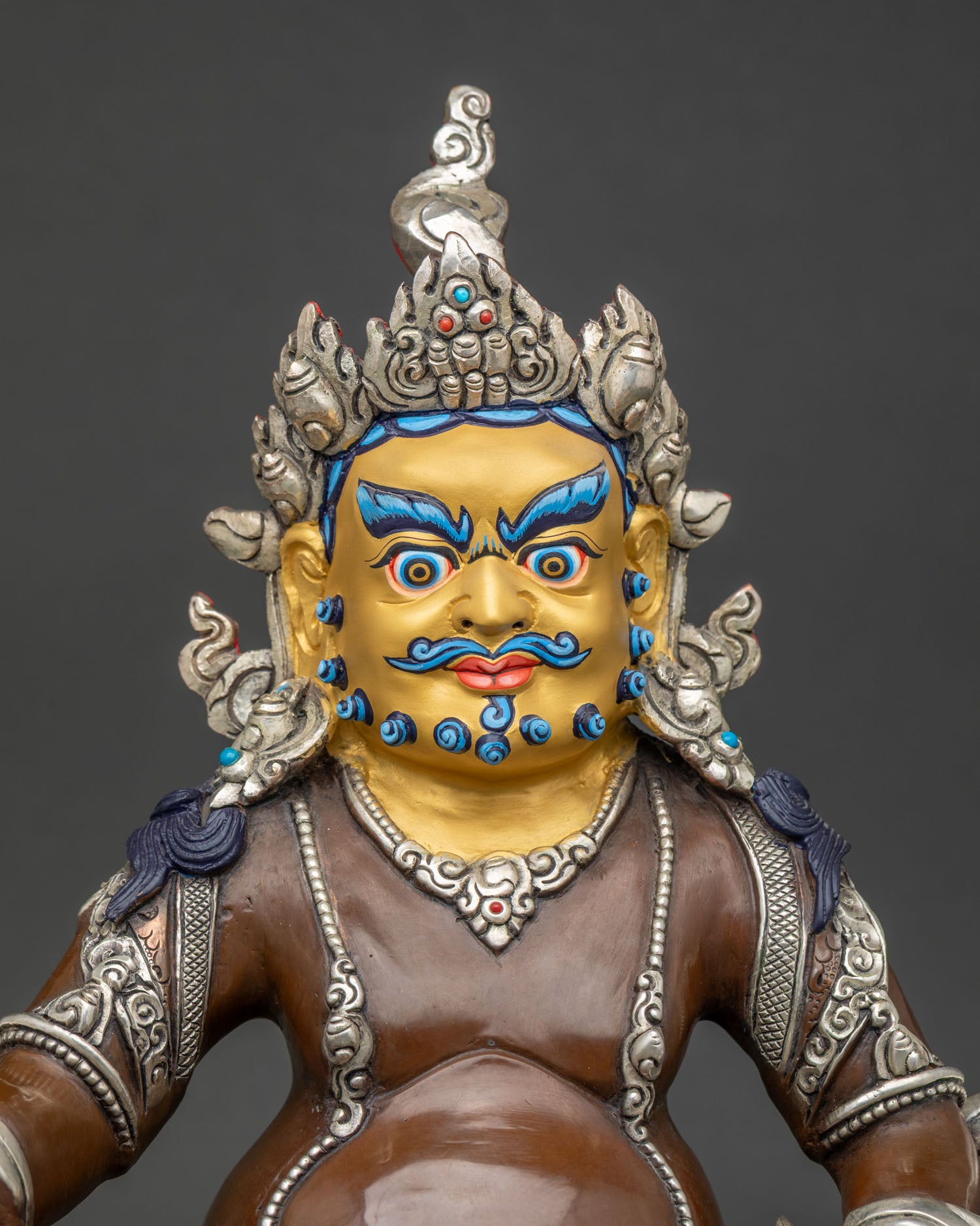 Close up of Jambhala wealth deity statue with serene expression and semi precious stone embellishments