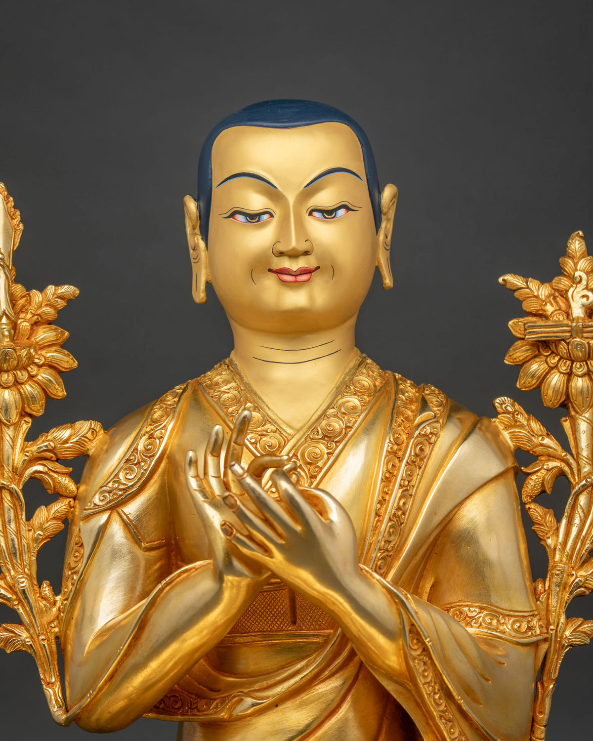 Close-up of Je Tsongkhapa’s gold face, deep blue hair, and soft, knowing eyes, hands poised at his heart