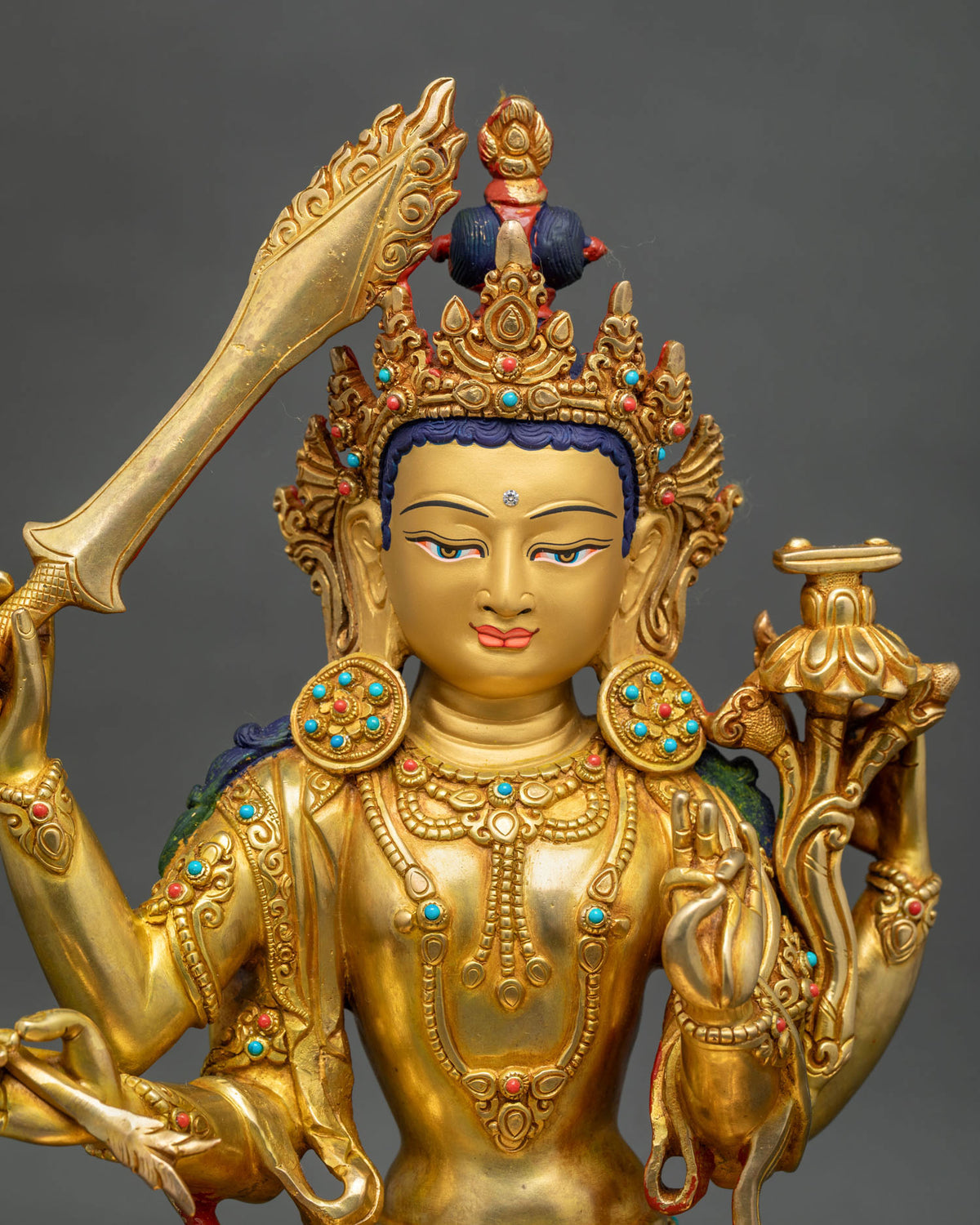 Close up of Maha Manjushri copper statue with turquoise and coral inlay and gold fire-gilded robe detail