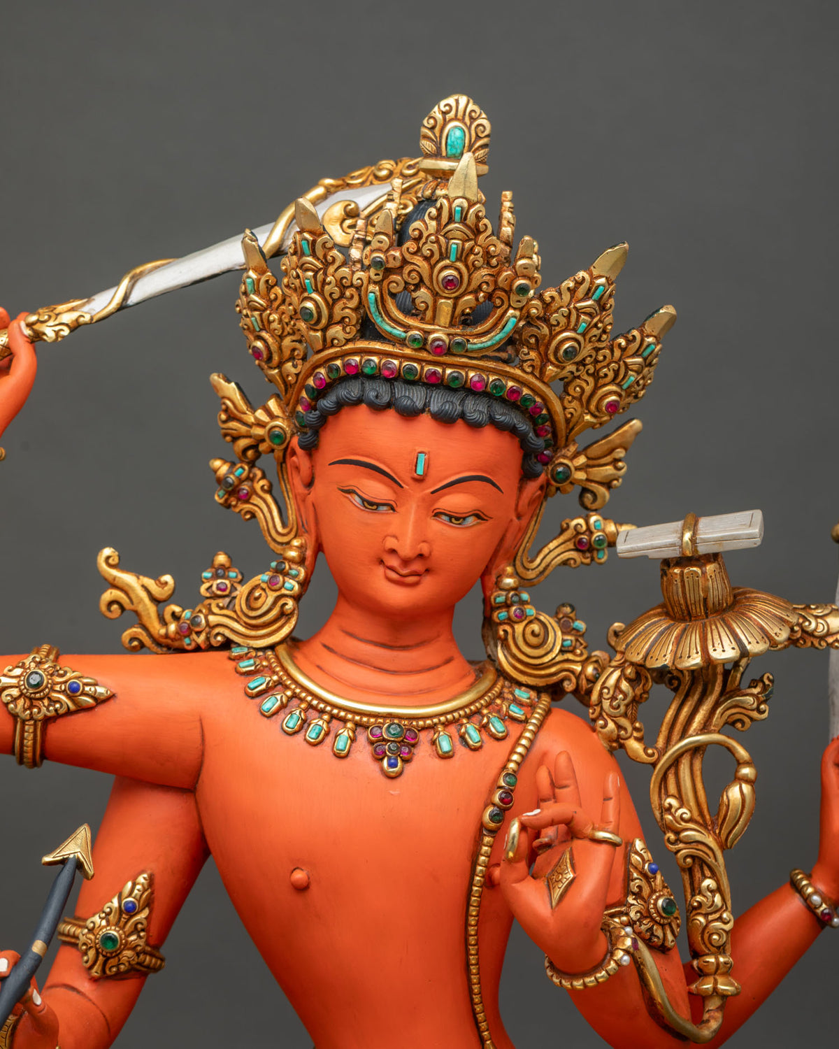 Close-up of Maha Manjushri statue with jeweled gold crown, gemstone necklace and raised wisdom sword