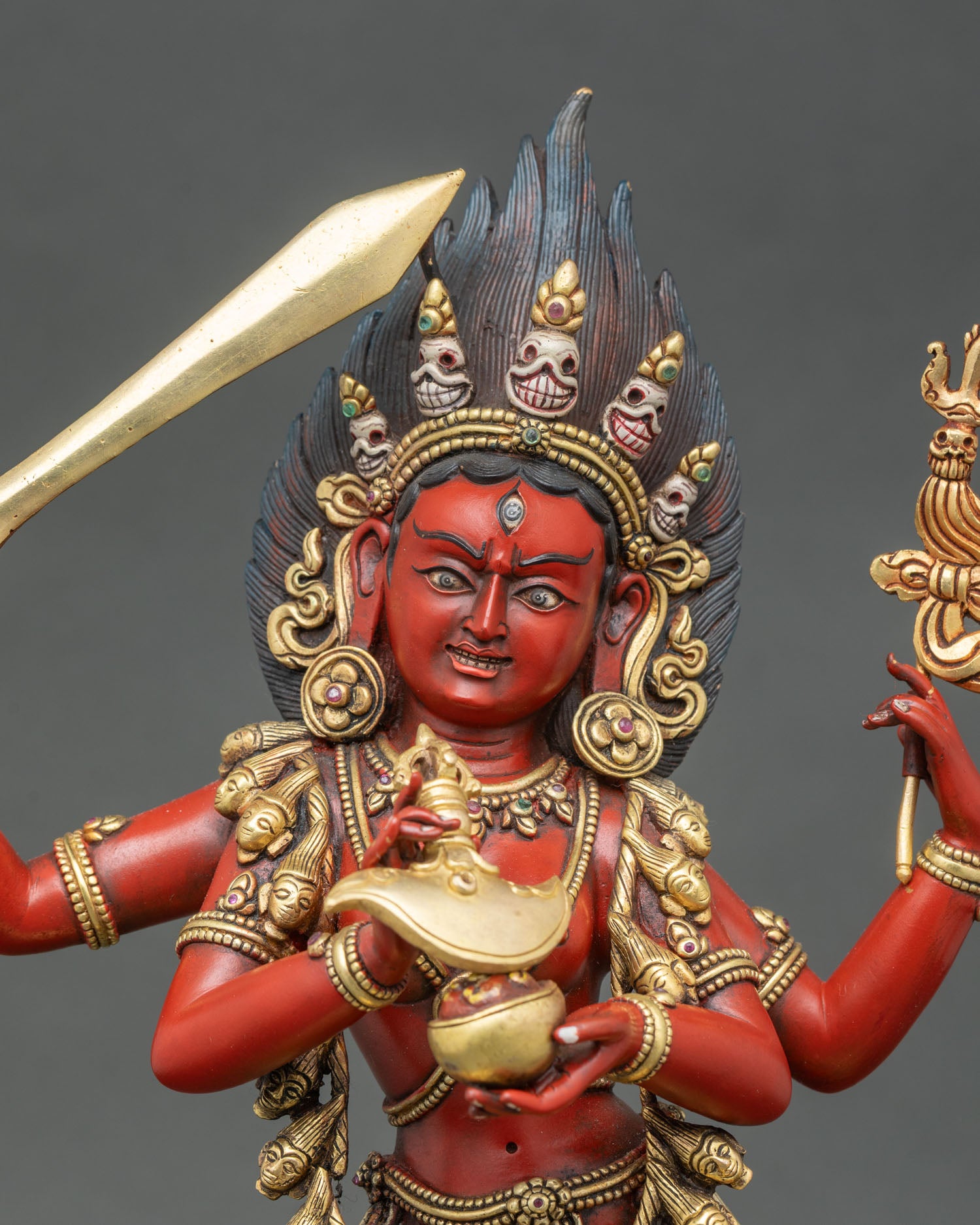 Close-up of Maha Vajravarahi statue showing four arms, ritual implements, and intricate gold detailing