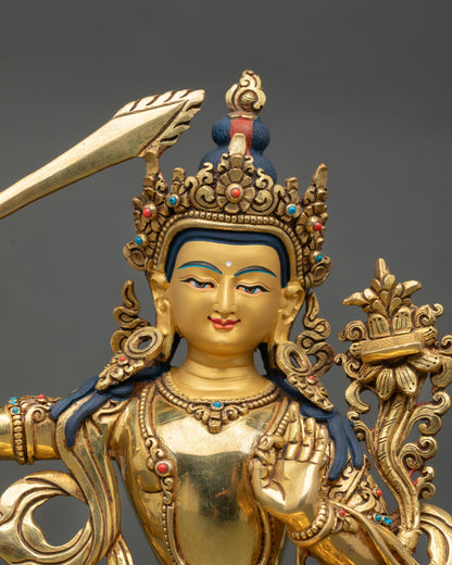 Close up of Manjushree statue showing gold painted face, semi precious stone inlays and detailed crown