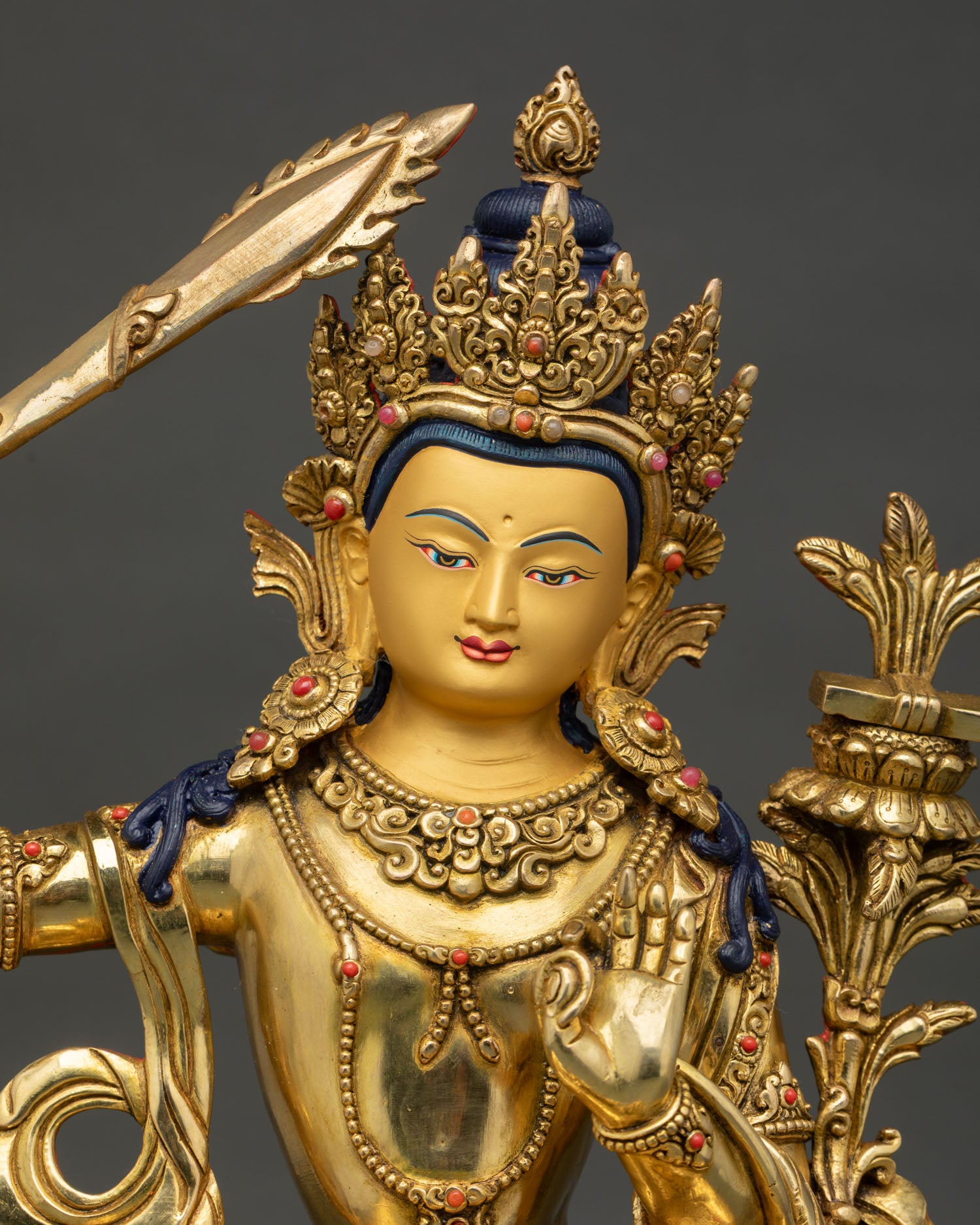 Close up of Manjushri Bodhisattva featuring gold painted face and five jeweled crown
