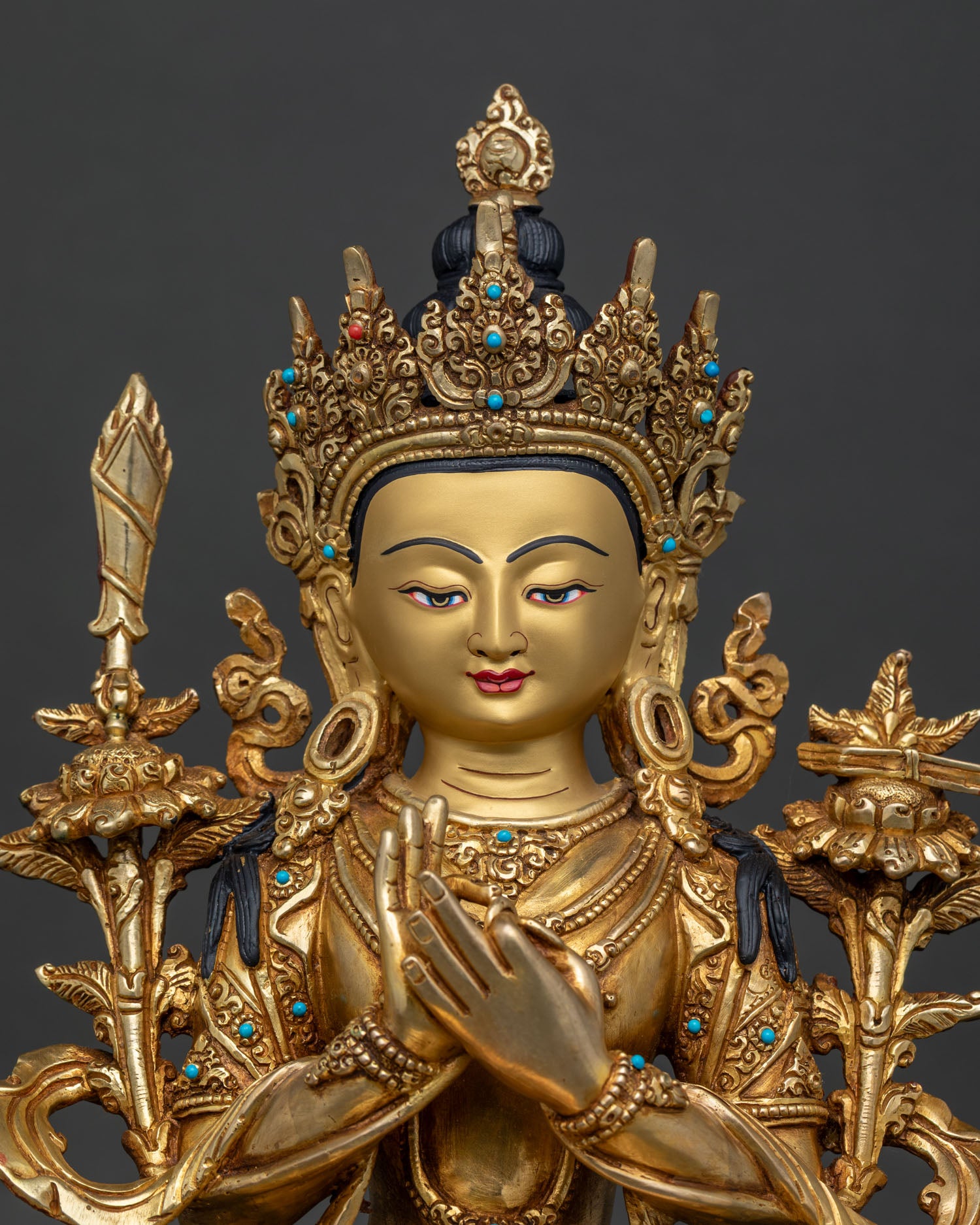 Close up of Manjushri Bodhisattva gold-painted face with Dharma Chakra Mudra and ornate lotus throne
