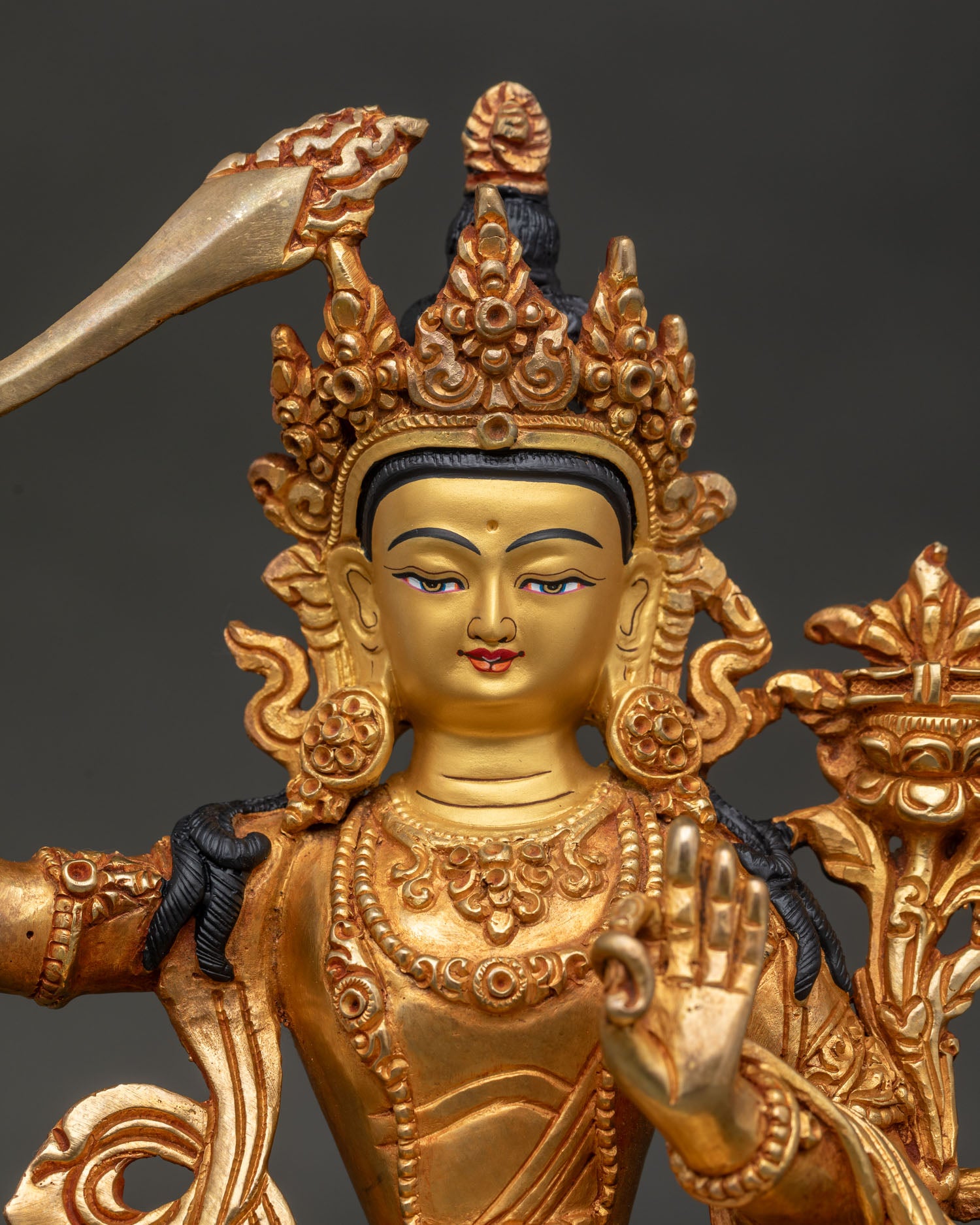 Close up of Manjushri Bodhisattva statue with gold painted face and Prajnaparamita Sutra