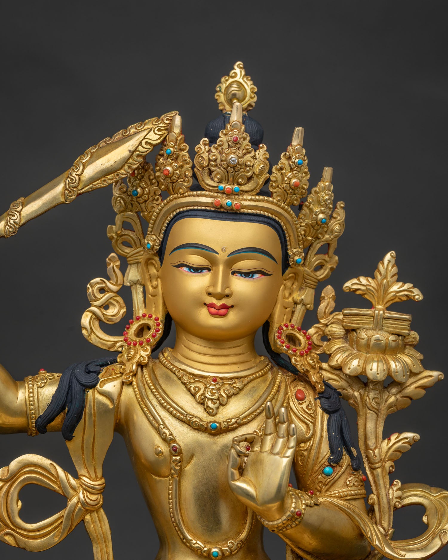 Close up of Manjushri Buddhist statue with gold painted face and intricate details
