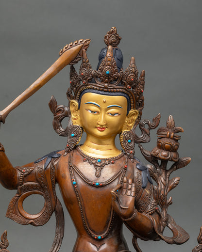 Close-up of Manjushri statue showing gold-painted face and semi-precious stone details.
