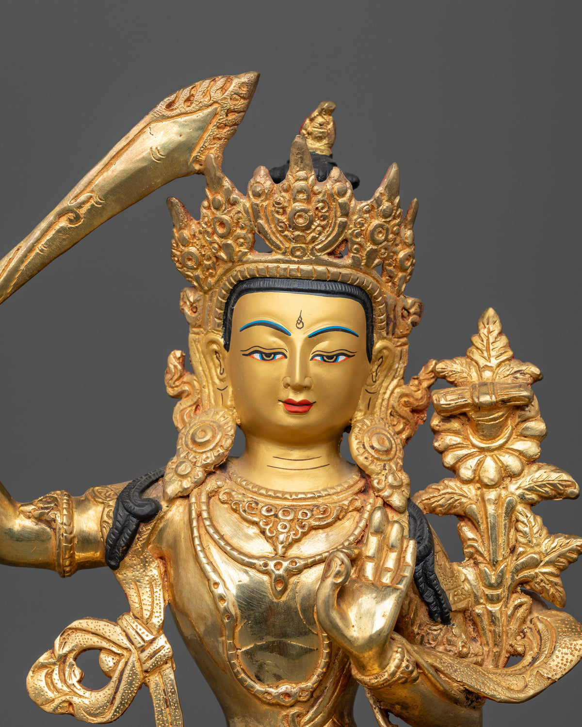 Close up of Manjushri Statue with 24K gold face and carved floral robe.