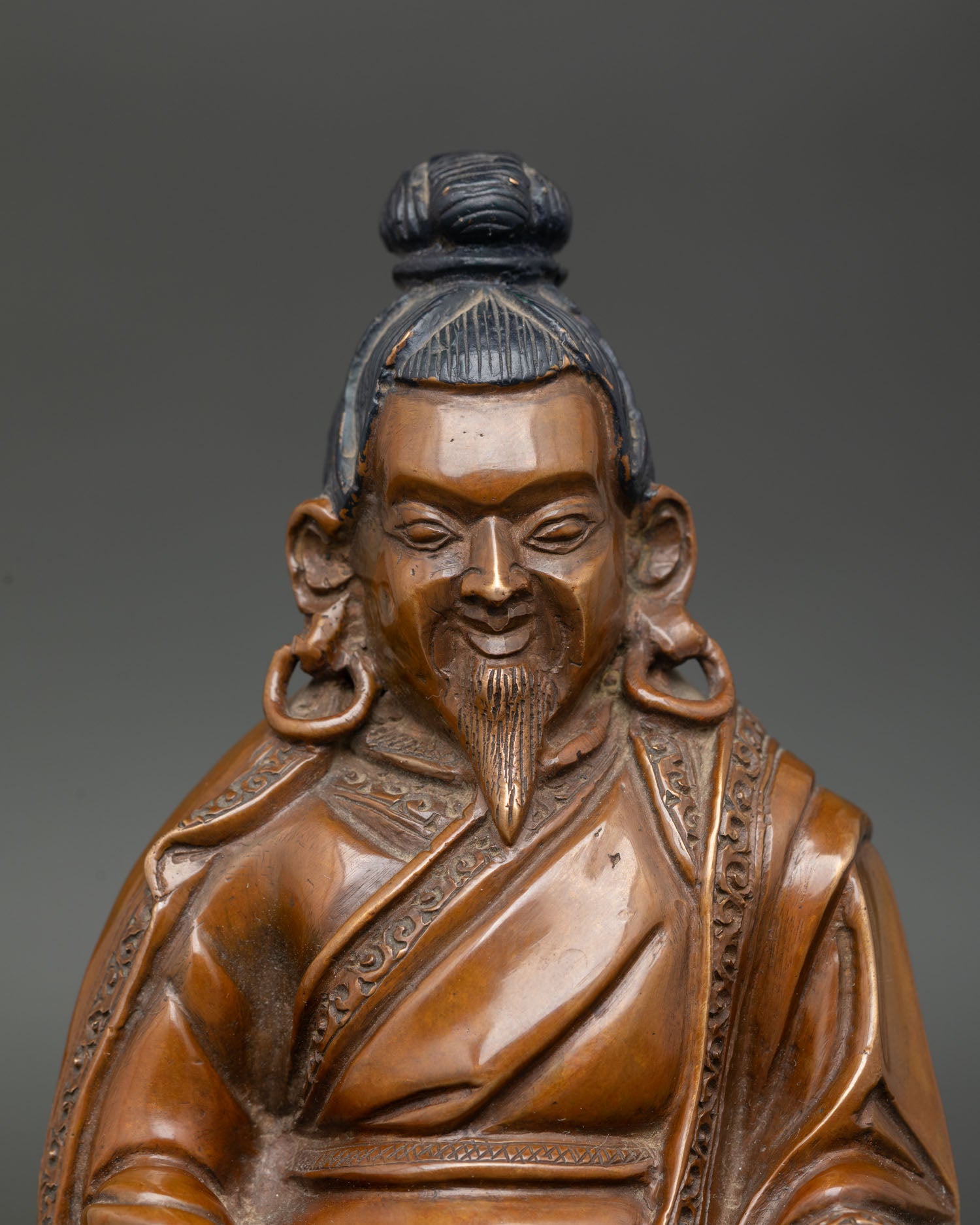 Close up of Marpa Buddhist statue, showing detailed monk robes and peaceful expression