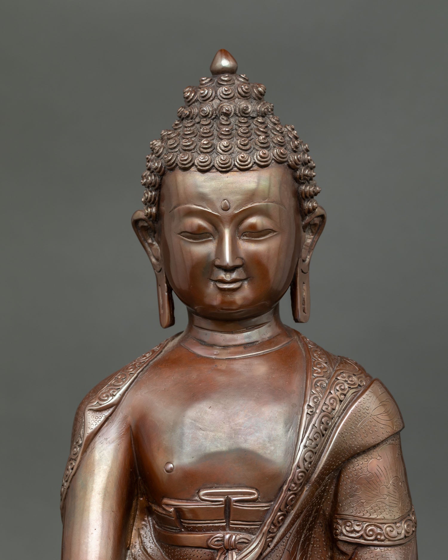 Close up of Medicine Buddha face, detail serene expression oxidized Buddhist sculpture Nepal artisan craftsmanship.