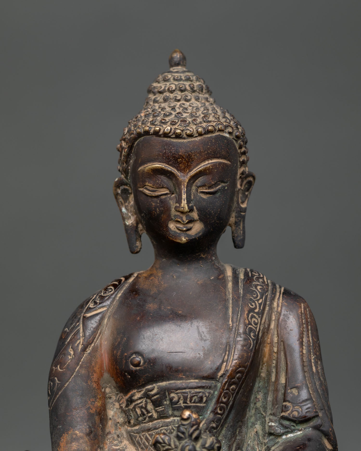 Close-up of Medicine Buddha face with intricately detailed monastery robe and antique finish.