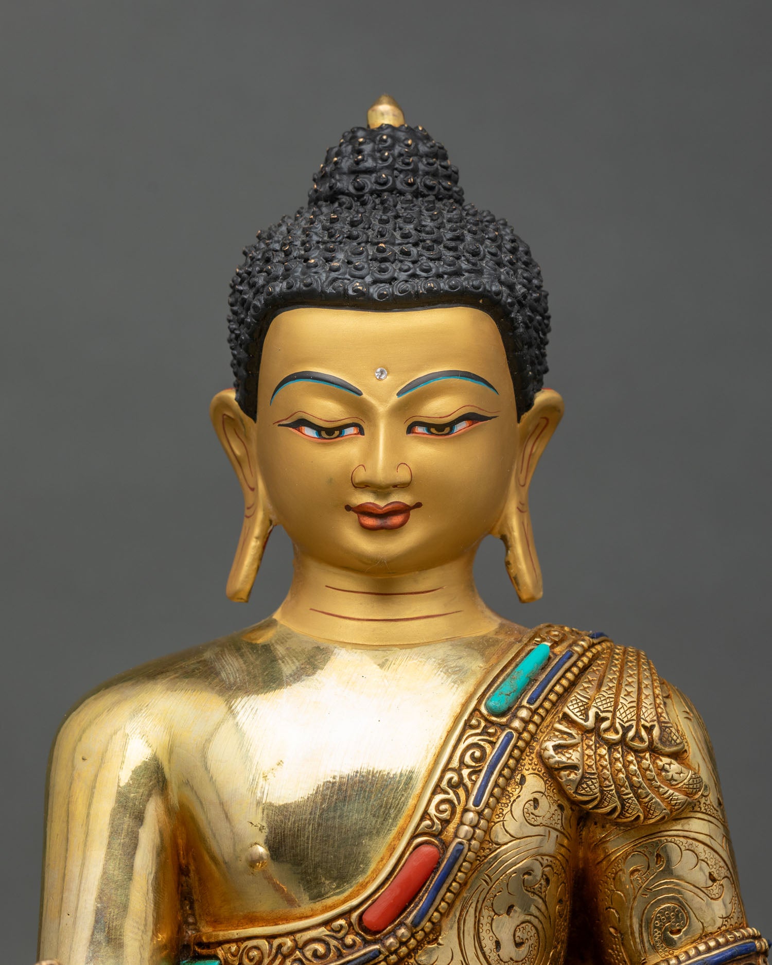 Close-up of Medicine Buddha statue showing gold fire-gilding and jeweled halo details