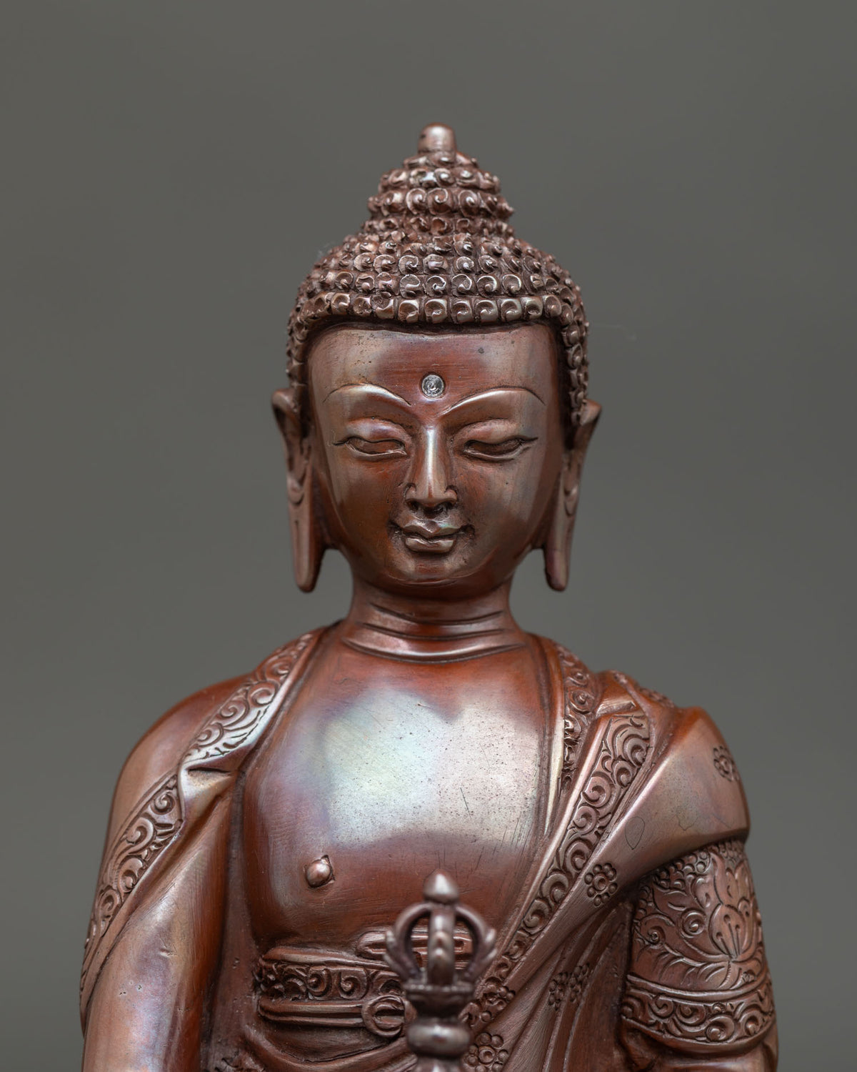 Close up of mitrugpa serene face and detailed buddhist ornaments with oxidized copper finish.