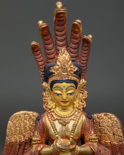 Close-up of Naga Kanya statue with five serpent crown, gold-painted face and conch shell.