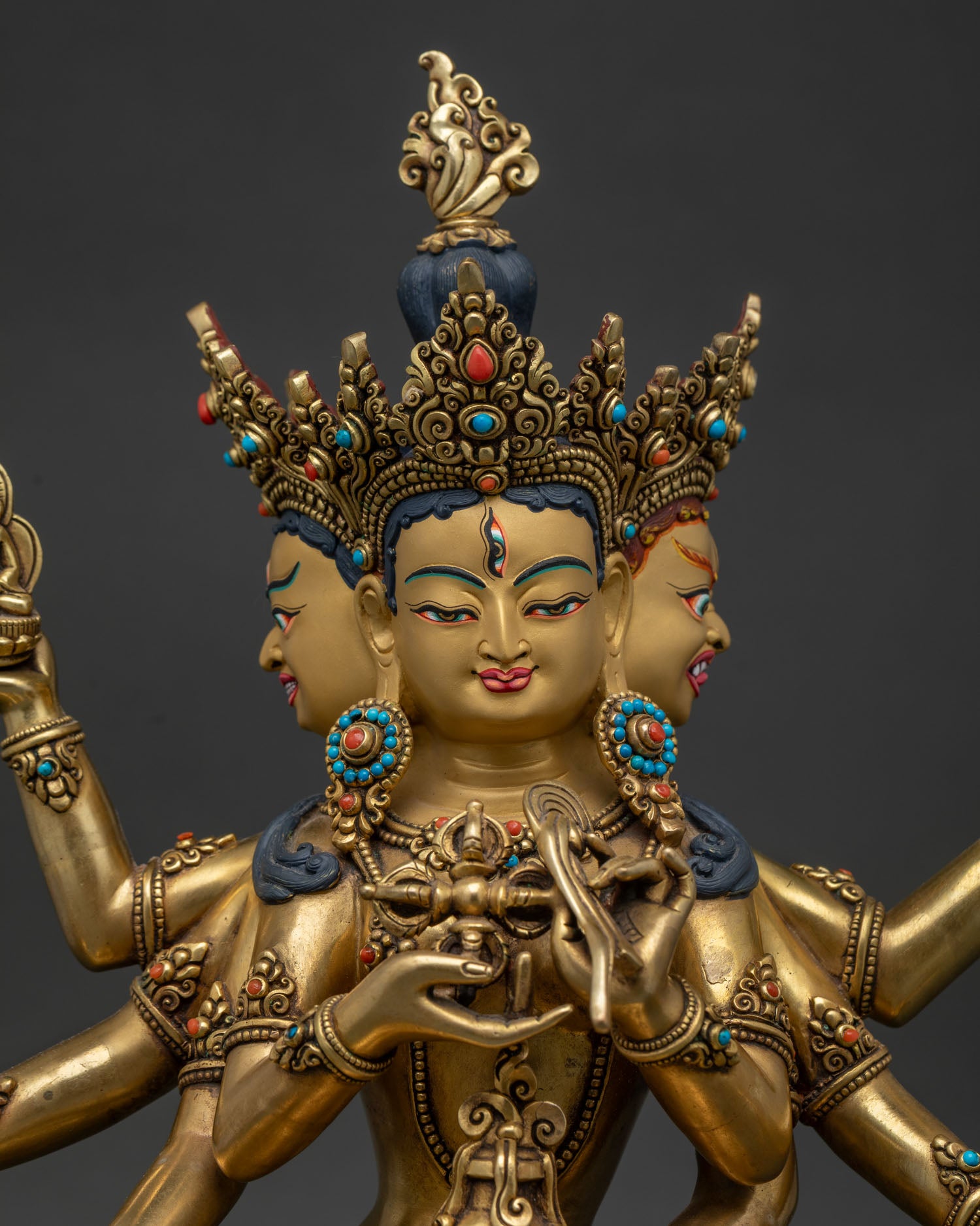 Close up of Namgyalma Buddhist deity statue with three faces and gold painted details
