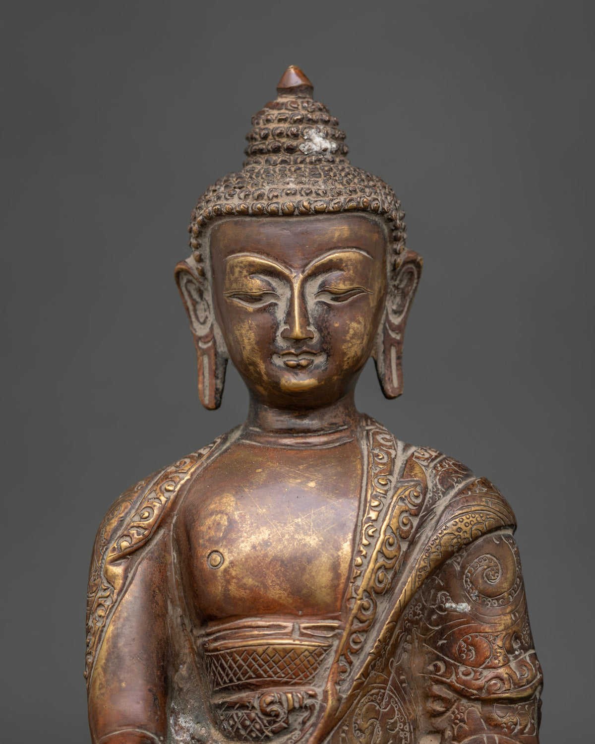 Close-up of Nepalese Shakyamuni Buddha statue featuring intricate carvings and an antique oxidized copper finish.