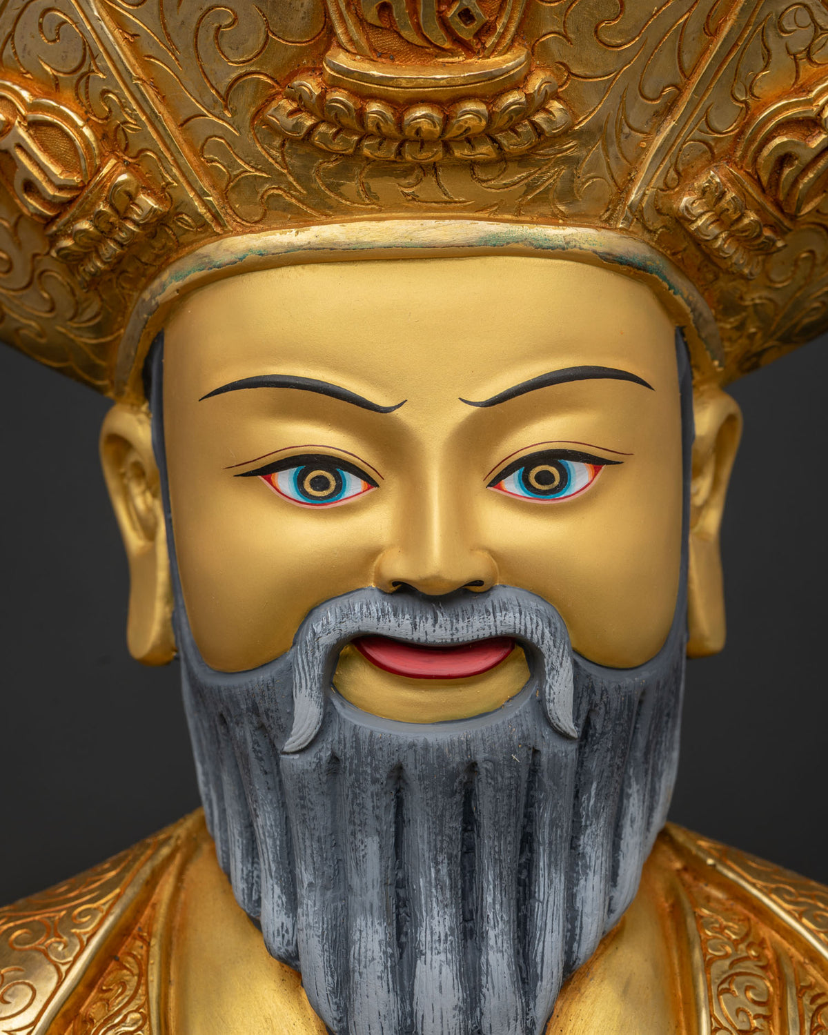 Close-up of Ngawang Namgyal's serene gold-painted face and crested lama hat