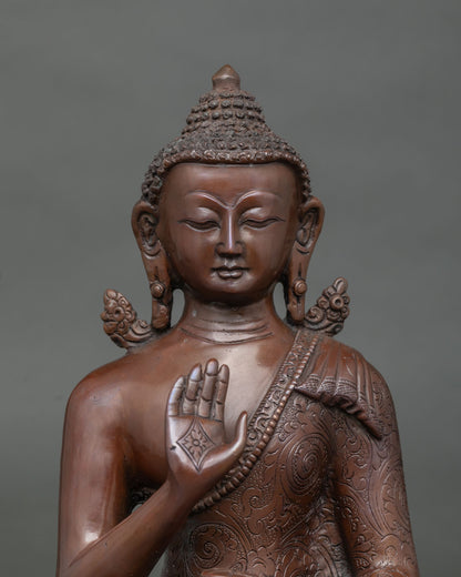 Close-up of oxidized copper Amoghasiddhi Buddha statue with raised hand and sacred bowl