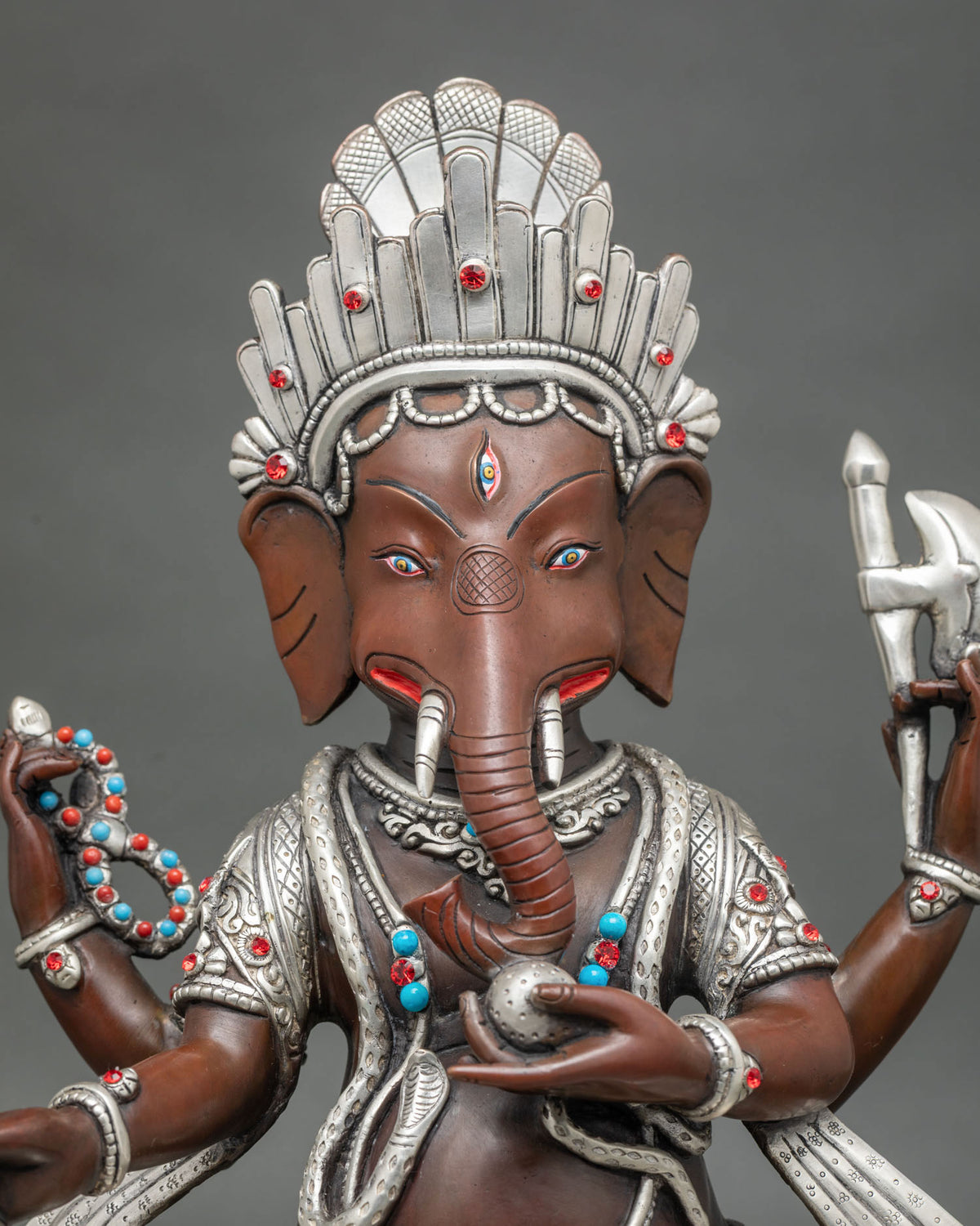 Close up of oxidized copper Ganesh idol with silver accents, ruby and turquoise stones, Newari art