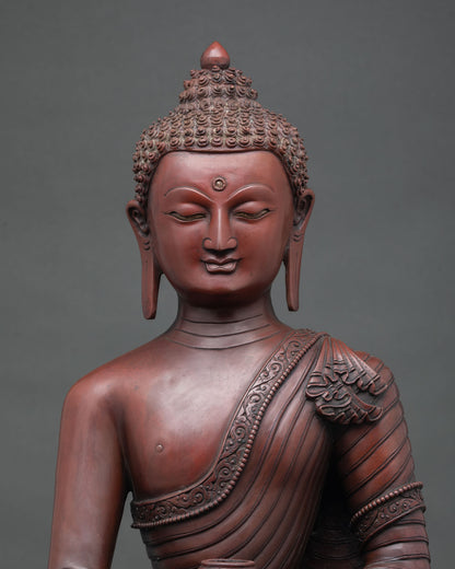 Close up of oxidized copper Shakyamuni Buddha statue serene expression and robe details