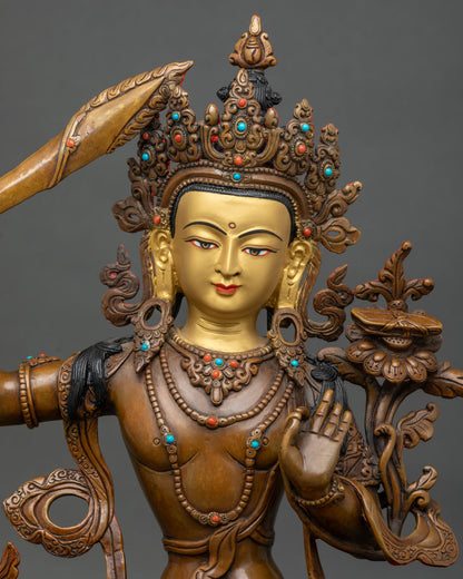 Close up of oxidized Manjushri copper statue with crown, flaming sword and lotus stem