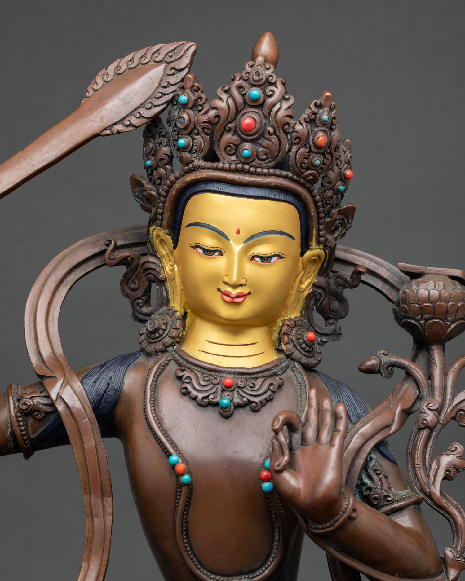 close up of oxidized manjushri statue with gold painted face and sacred details
