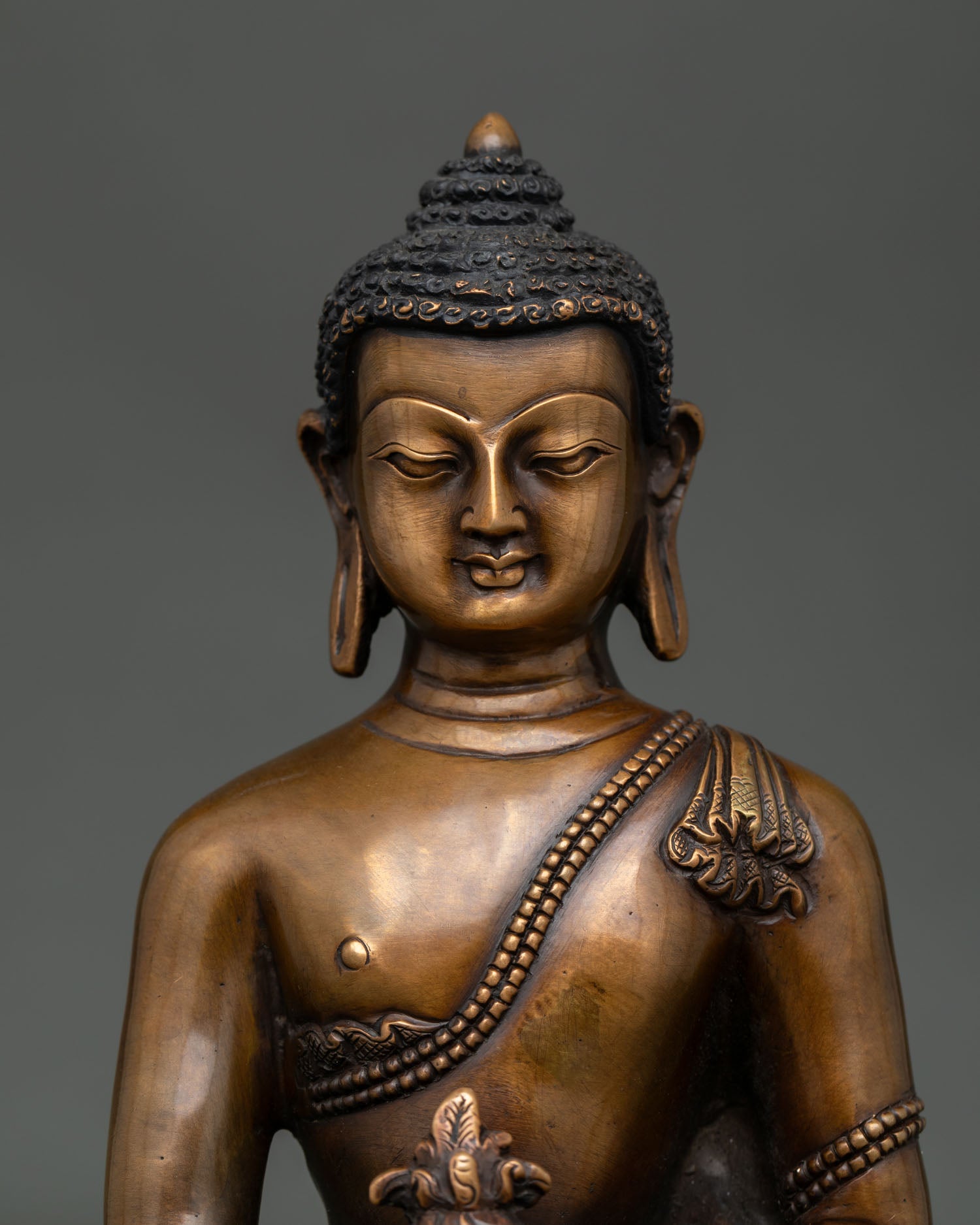 Close up of oxidized Medicine Buddha holding myrobalan plant and healing nectar bowl.