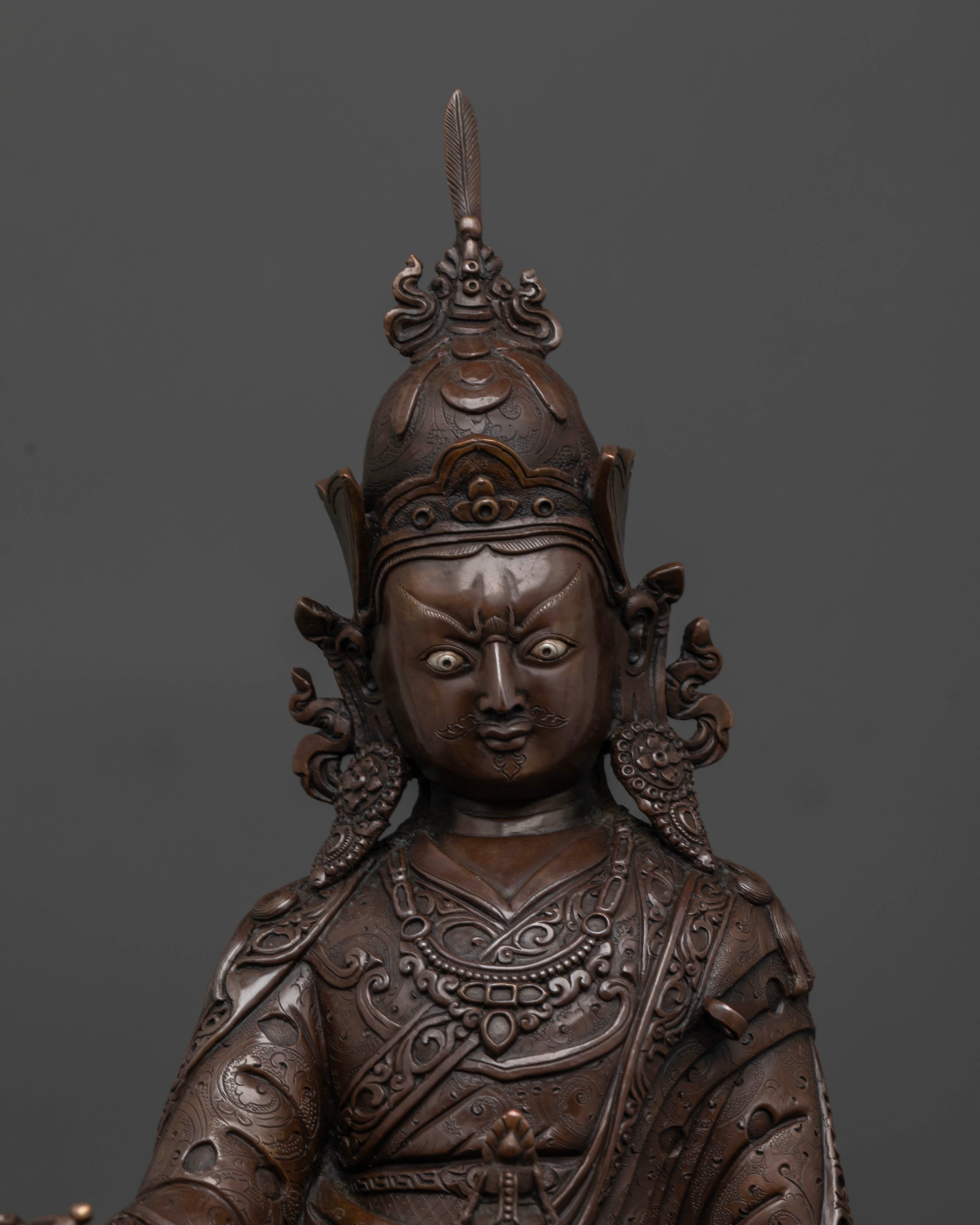 Close up of Padmasambhava statue showing semi wrathful face and sacred ornaments