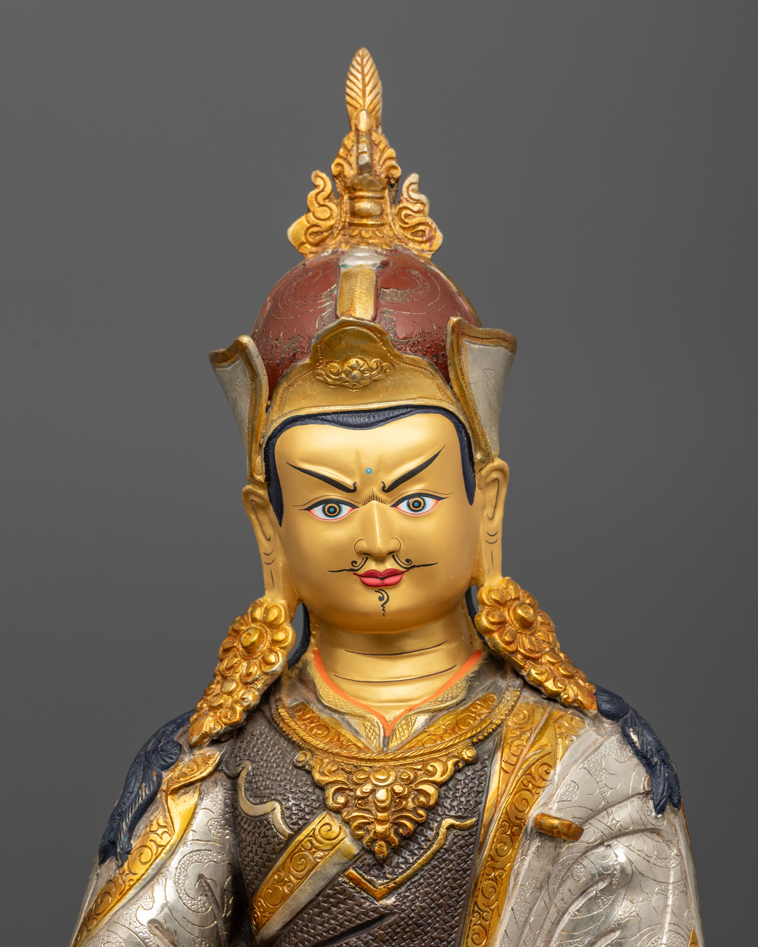 Close up of Padmasambhava Statue with gold painted face and intricate floral robe carvings