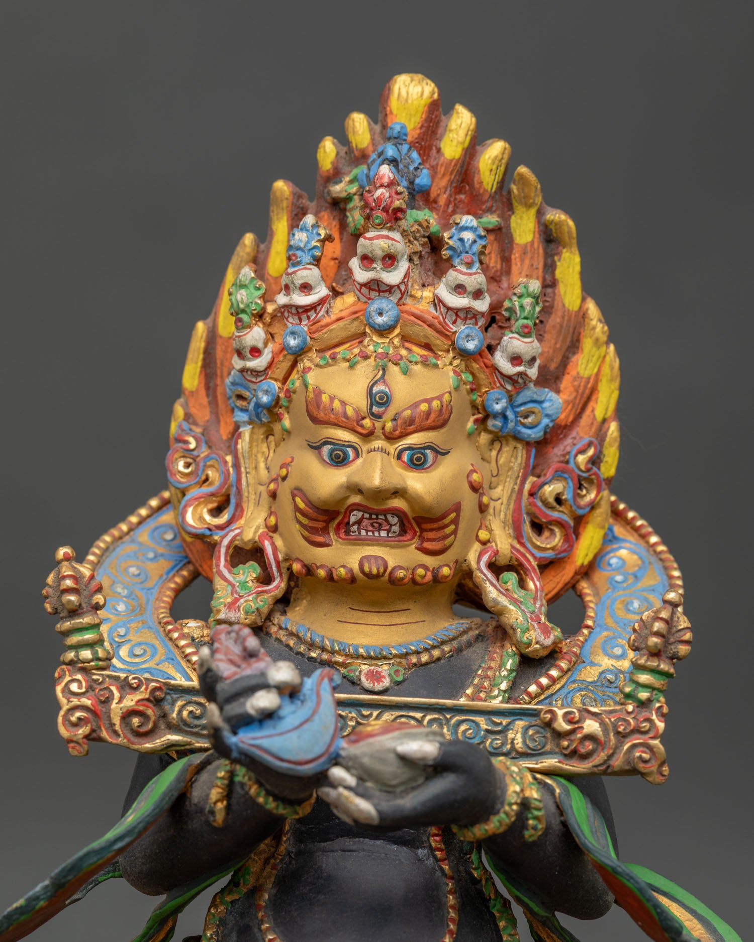 Close up of Sakya Mahakala face with three eyes, bared fangs, crown of five skulls 