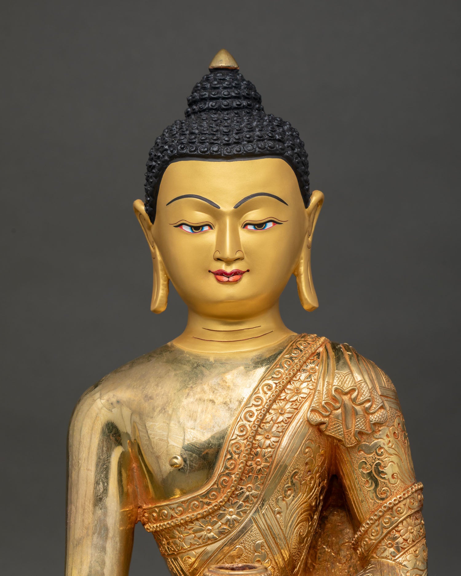 Close-up of serene gold-painted face of Buddha Shakyamuni statue with fine Himalayan craftsmanship details