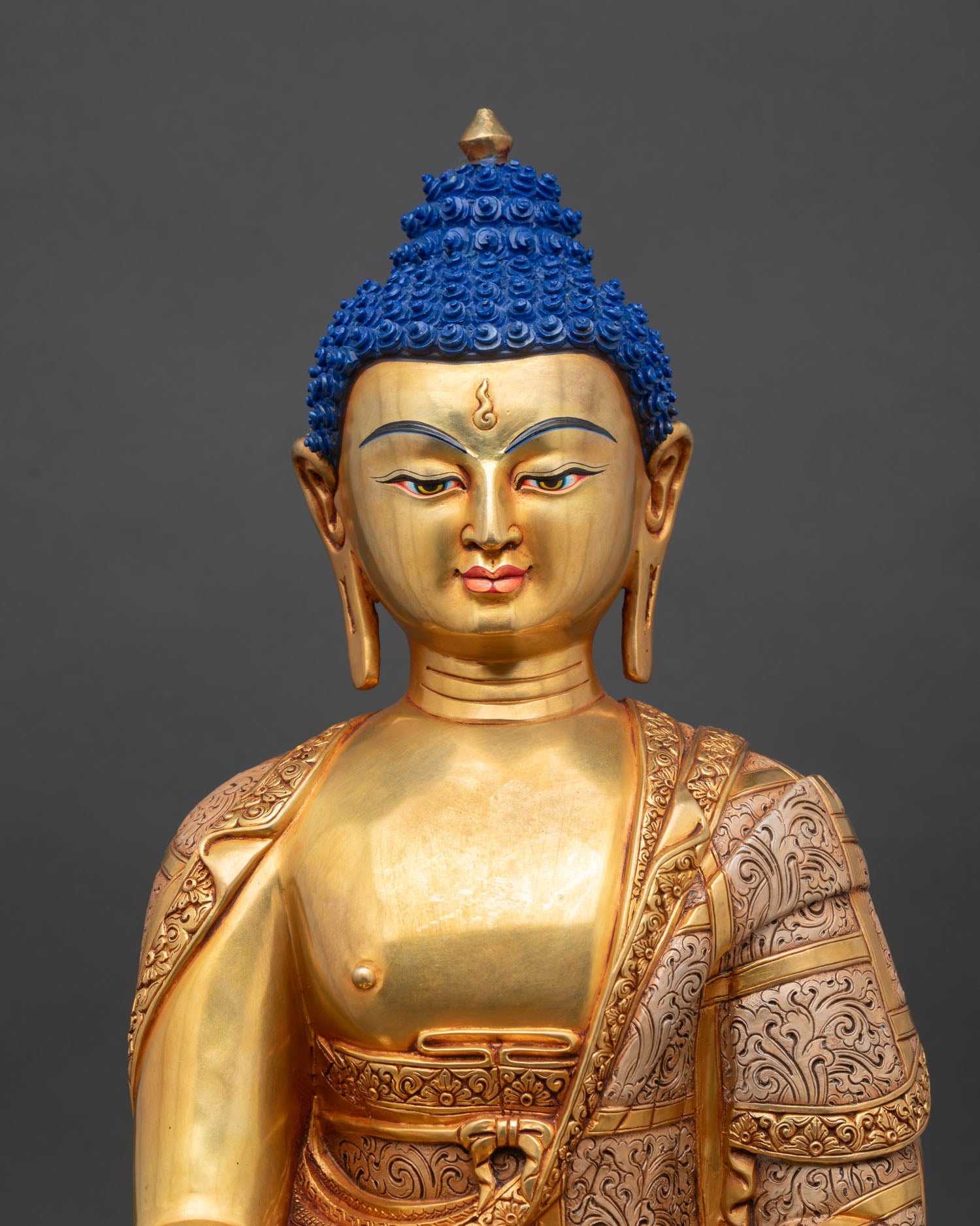 close-up of shakya buddha sculpture showing detailed copper and gold finish