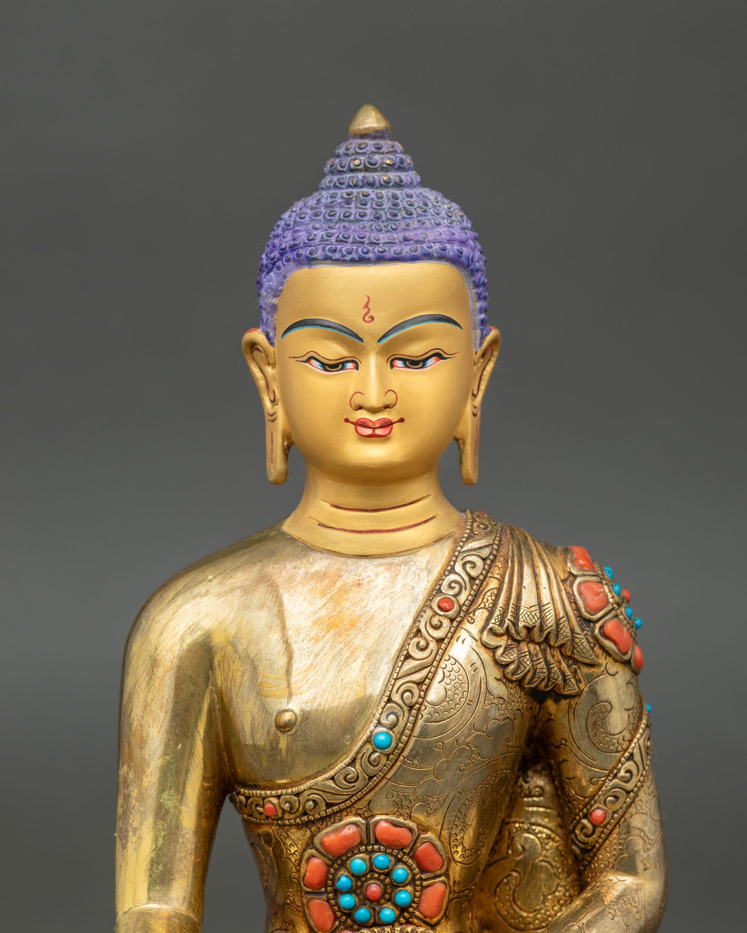 Close up of Shakyamuni Buddha face and embossed robes with turquoise and coral stones