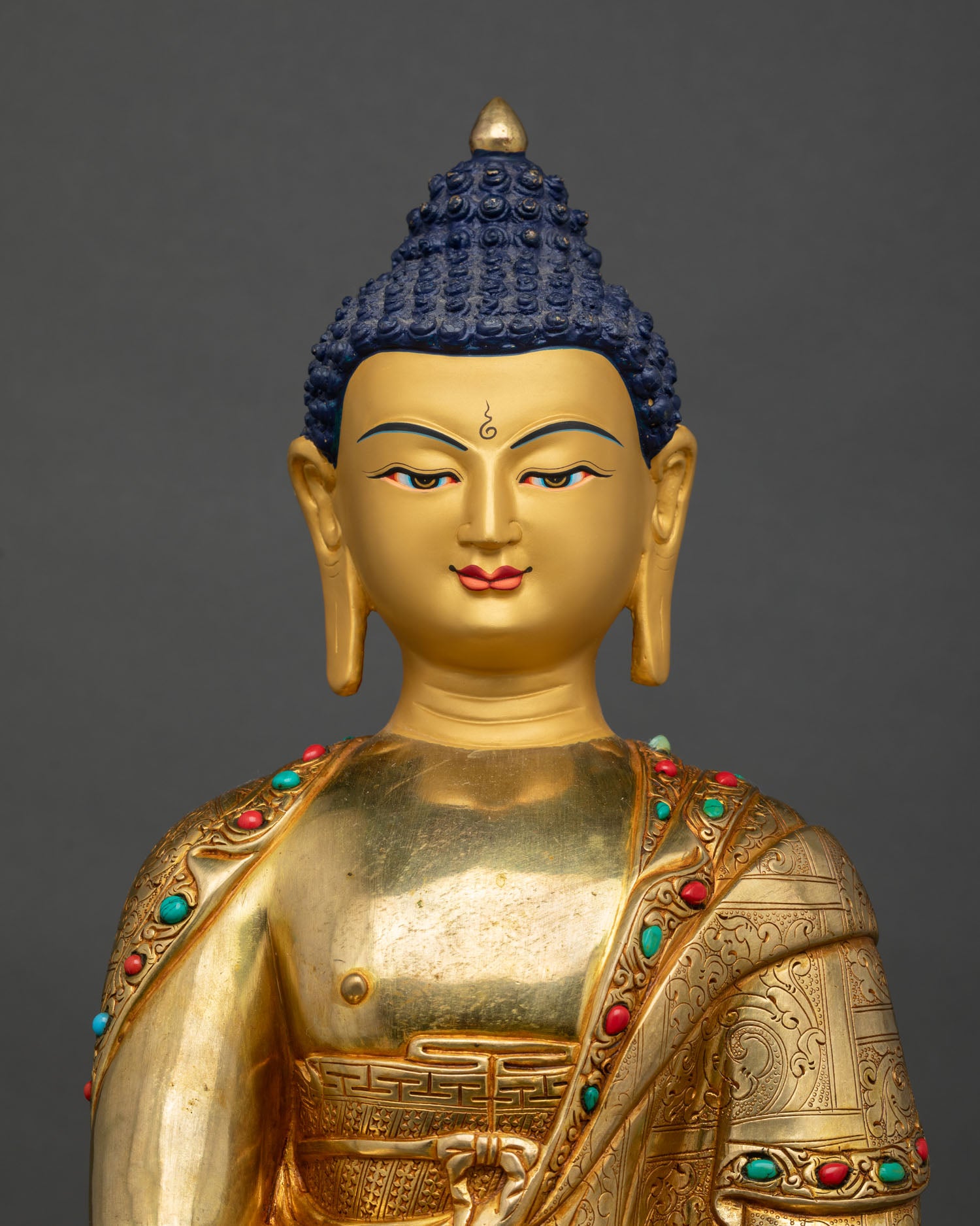 Close up of Shakyamuni Buddha face with gold gilded finish and serene enlightened expression