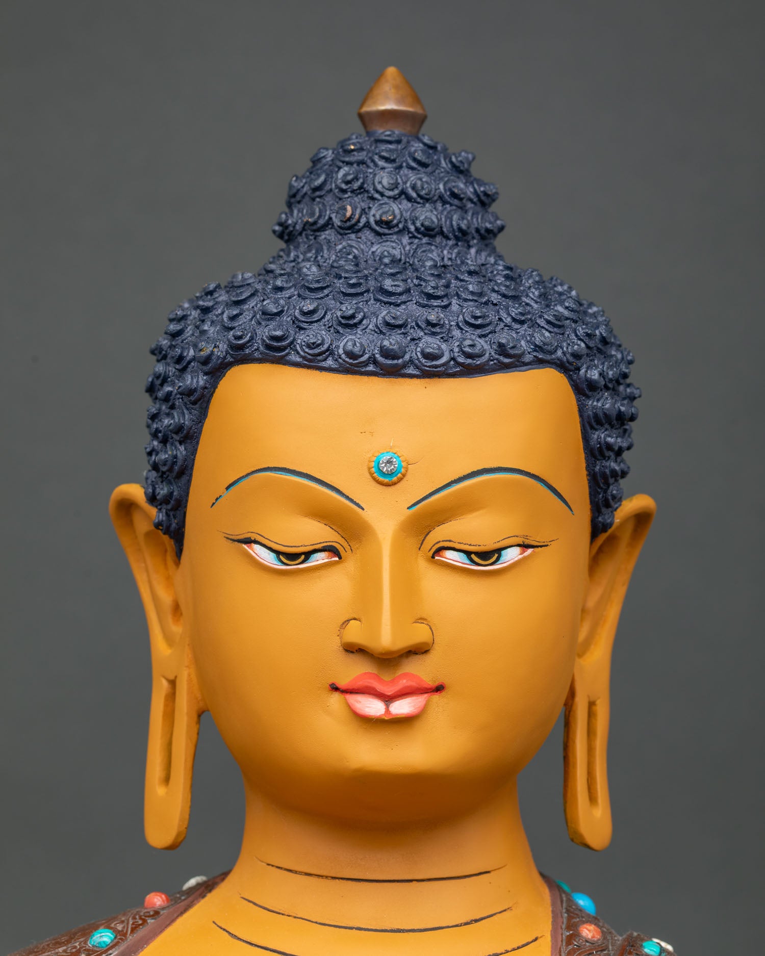 Close-up of Shakyamuni Buddha face with serene expression and vibrant acrylic-painted finish