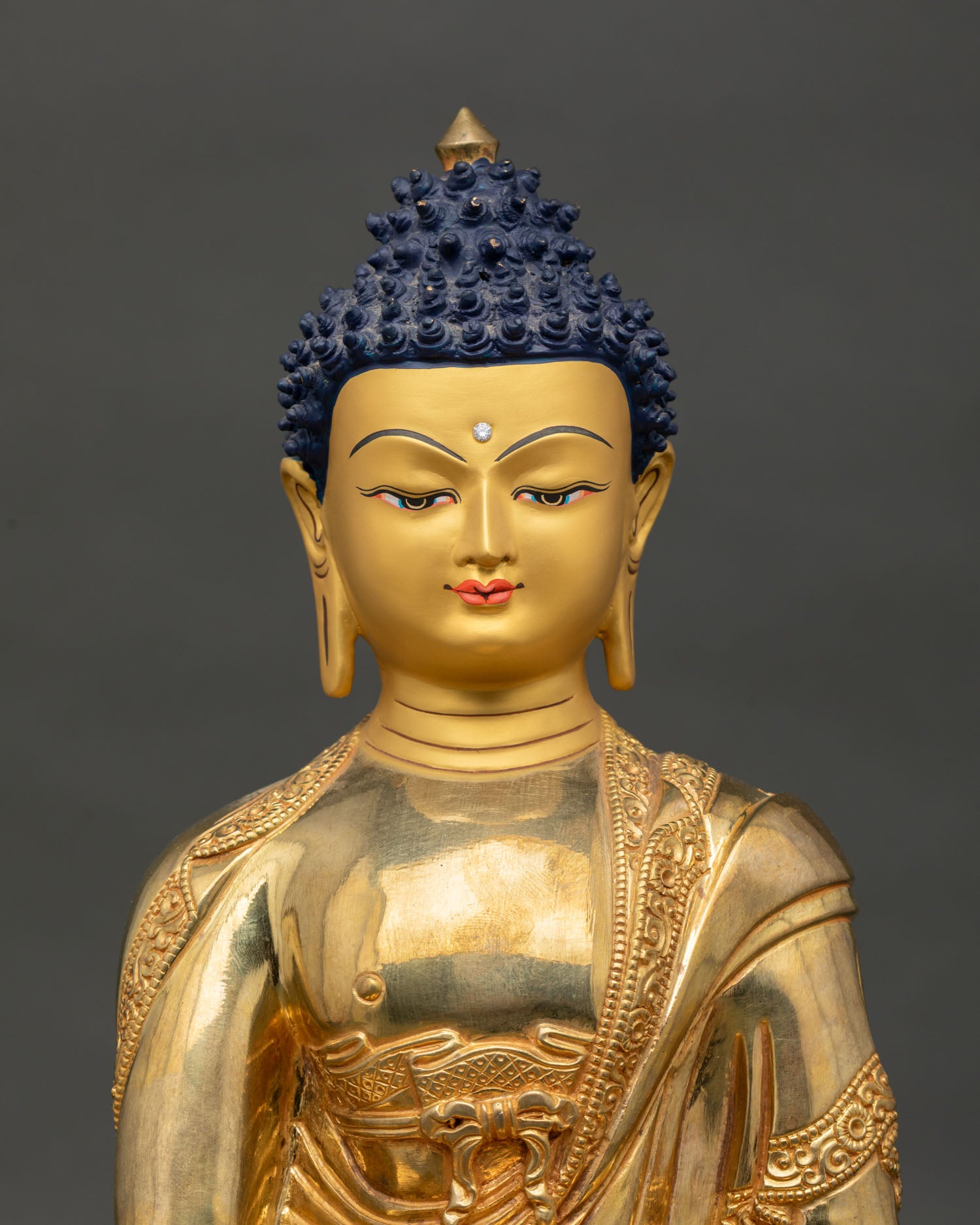 Close up of Shakyamuni Buddha gold painted face with serene expression and Buddhist details