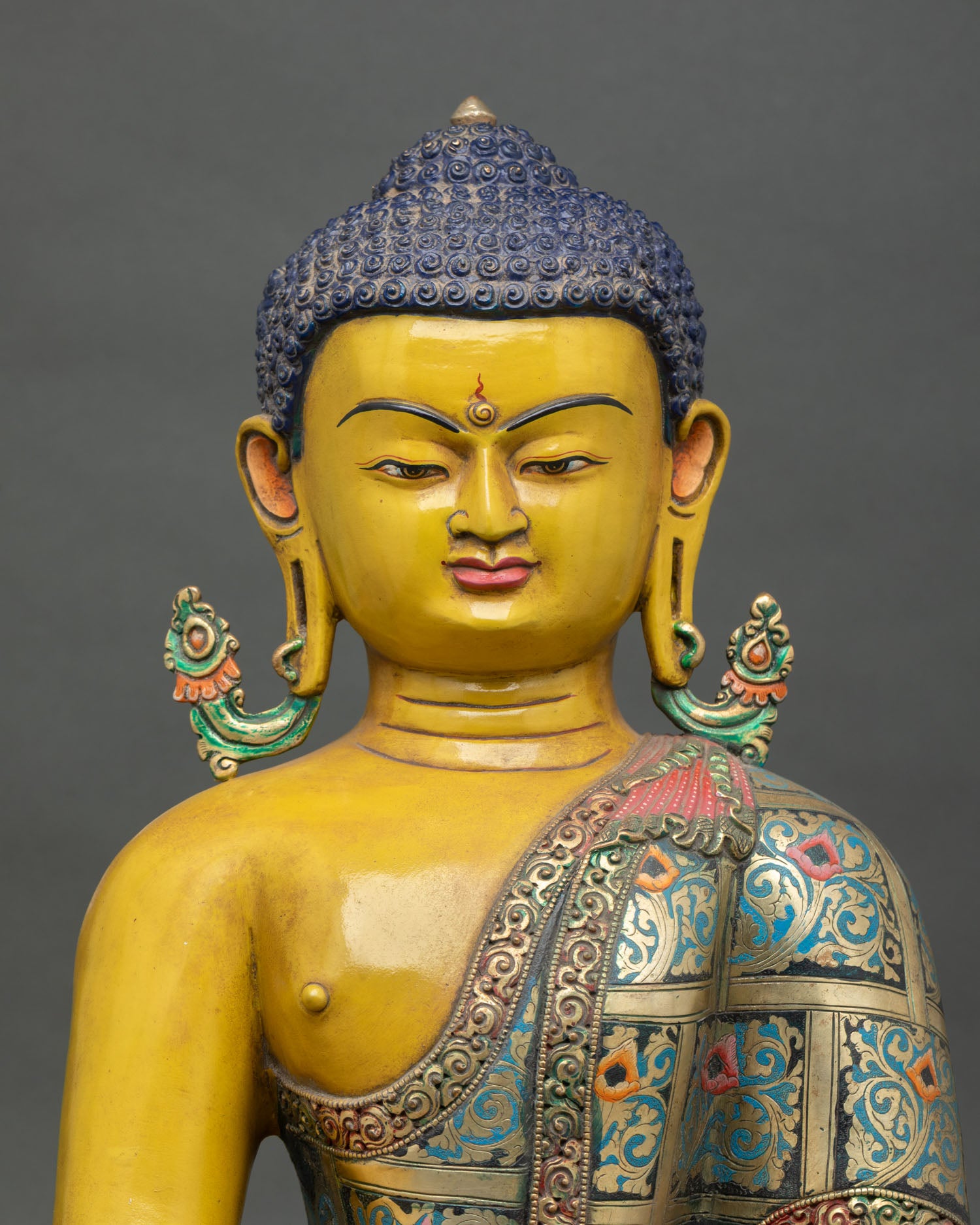 Close up of Shakyamuni Buddha serene face with elongated earlobes and traditional Newari craftsmanship