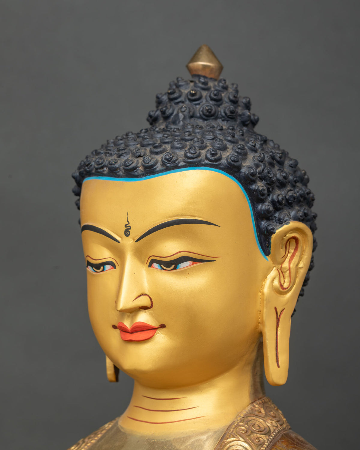 Close up of Shakyamuni Buddha statue with 24K gold painted face.