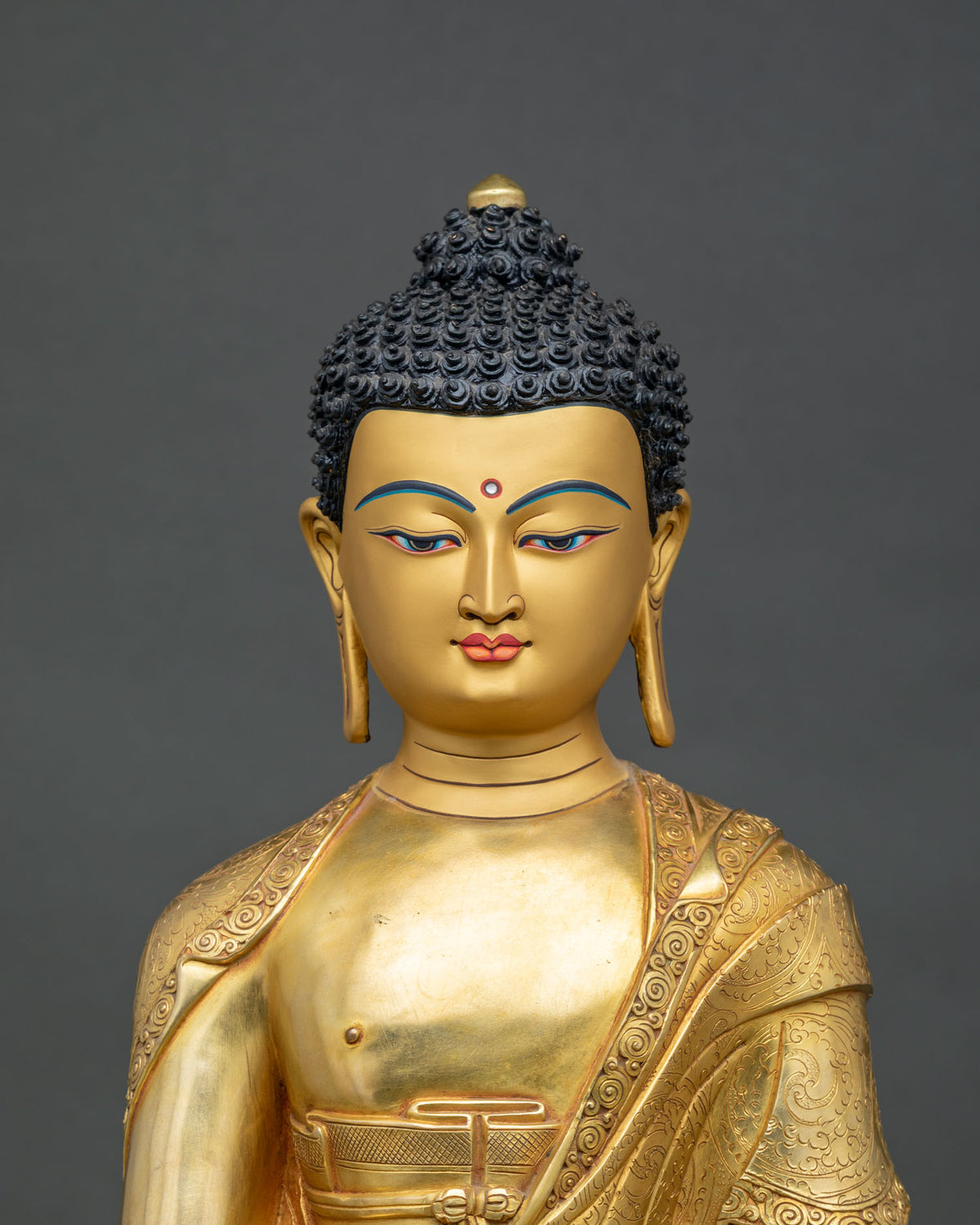 Close-up of Shakyamuni Buddha statue gold-painted face and hand-incised robe detail
