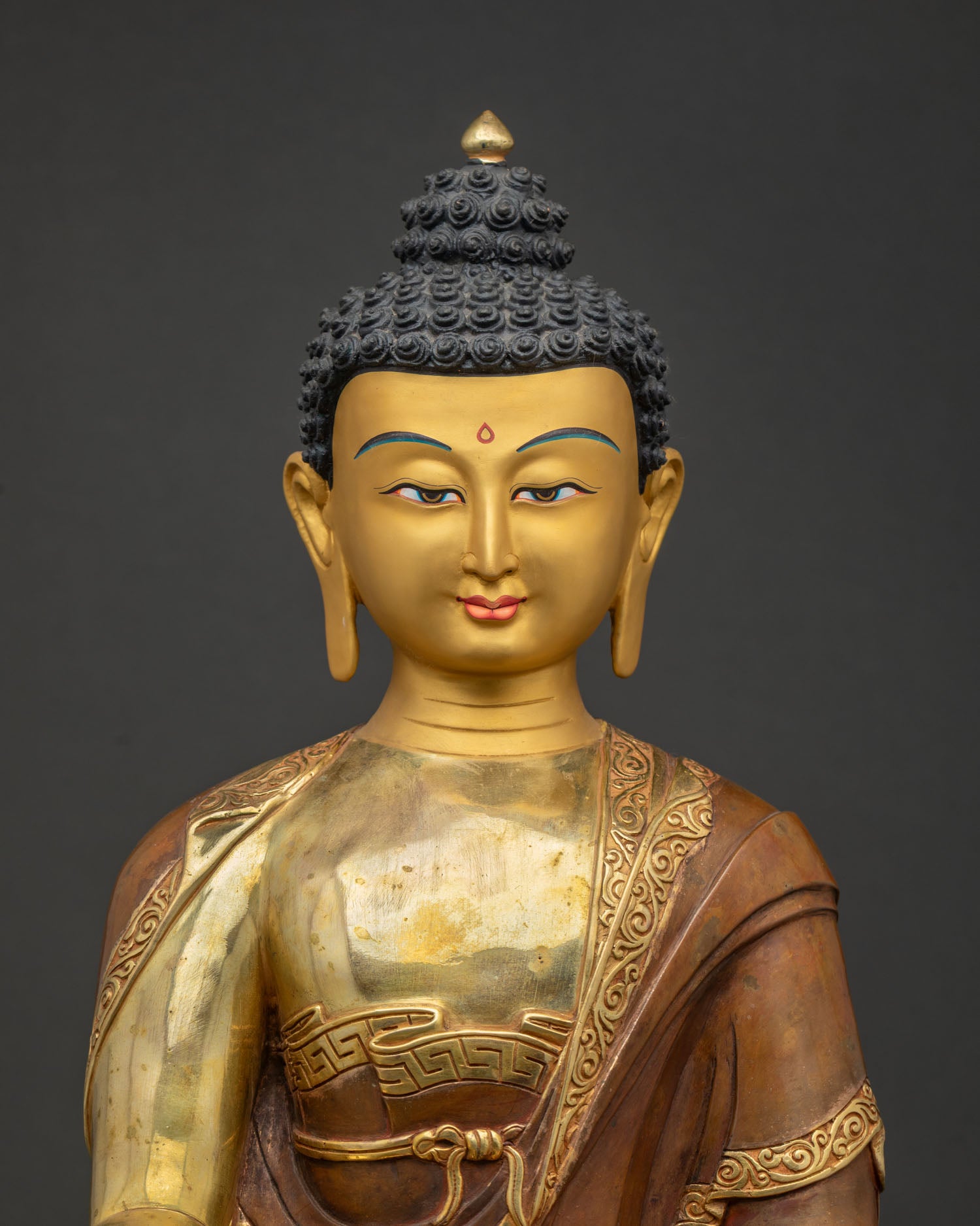 Close-up of Shakyamuni Buddha statue showing copper body and gold-gilded robe details