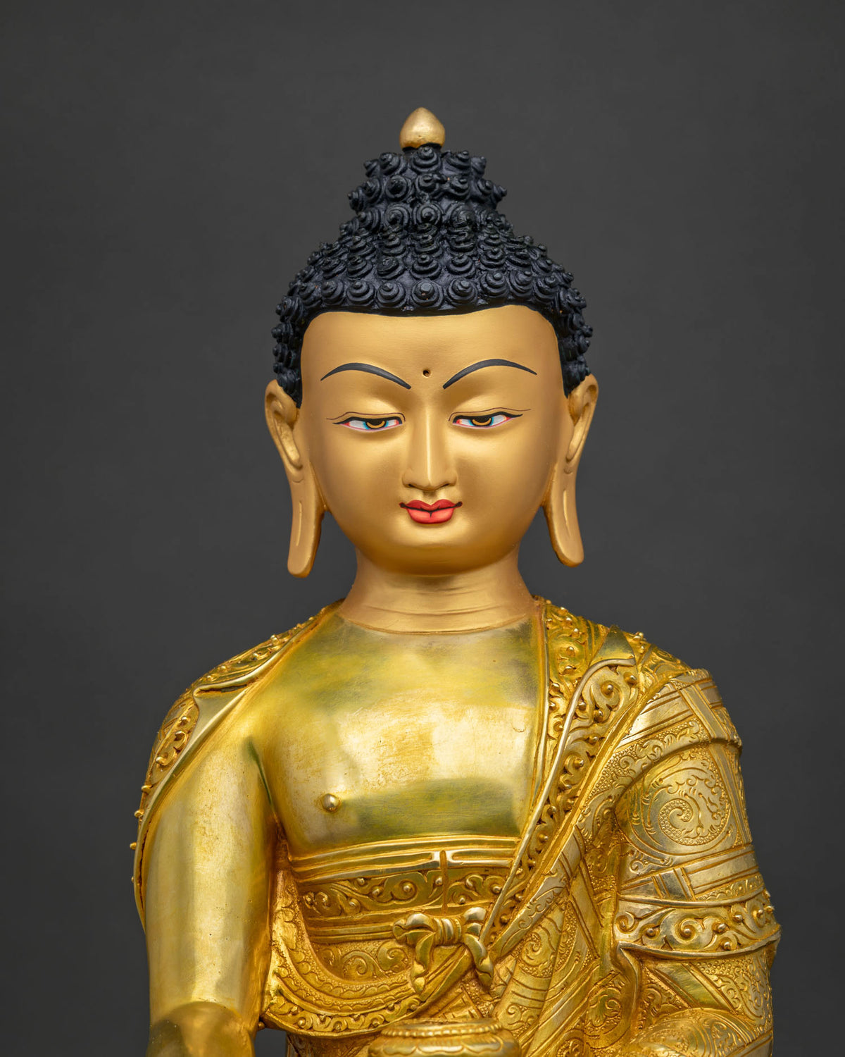 Close-up of Shakyamuni Buddha statue showing gold fire gilding and hand-carved robe details