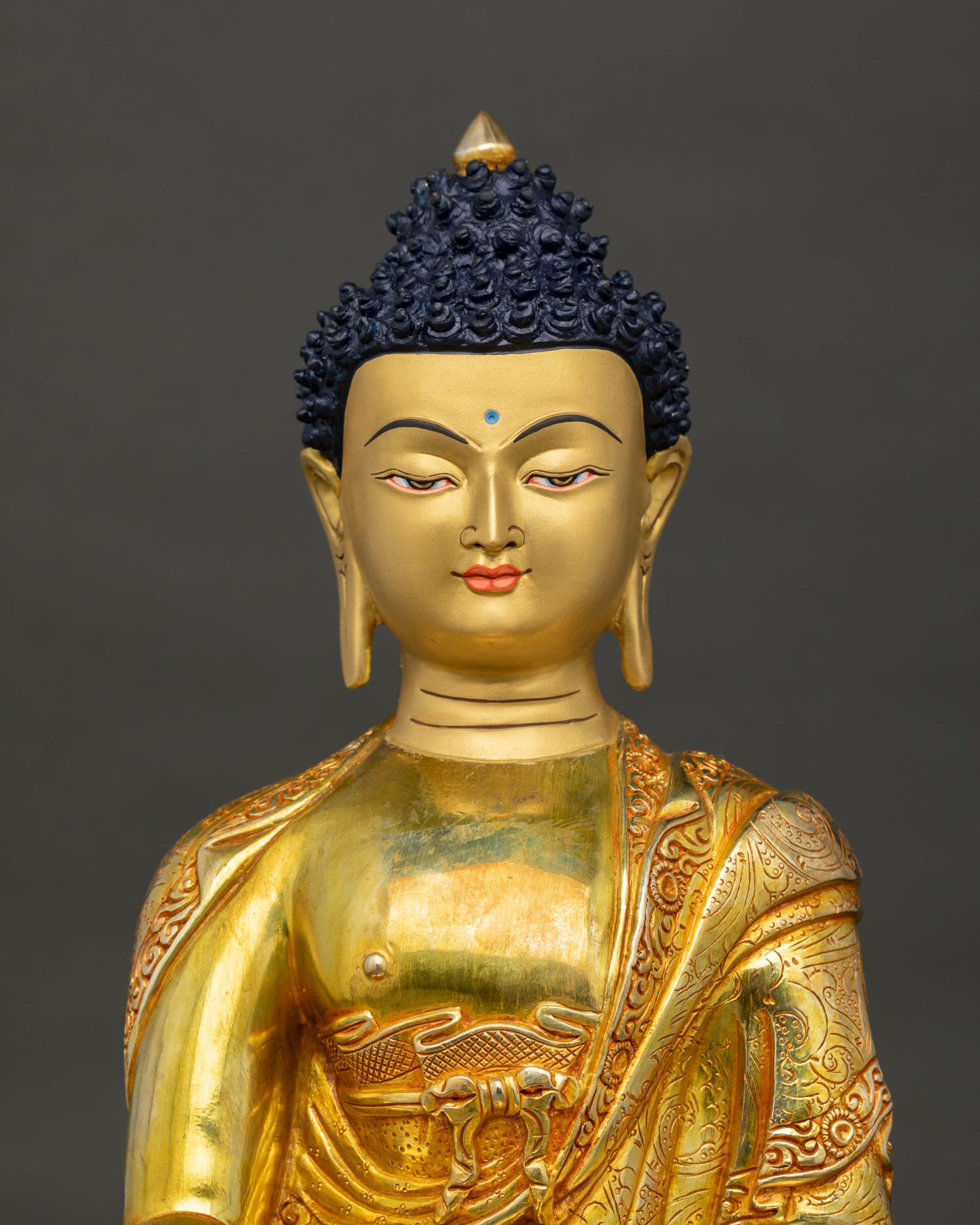 close up of shakyamuni buddha statue showing intricate copper and gold details