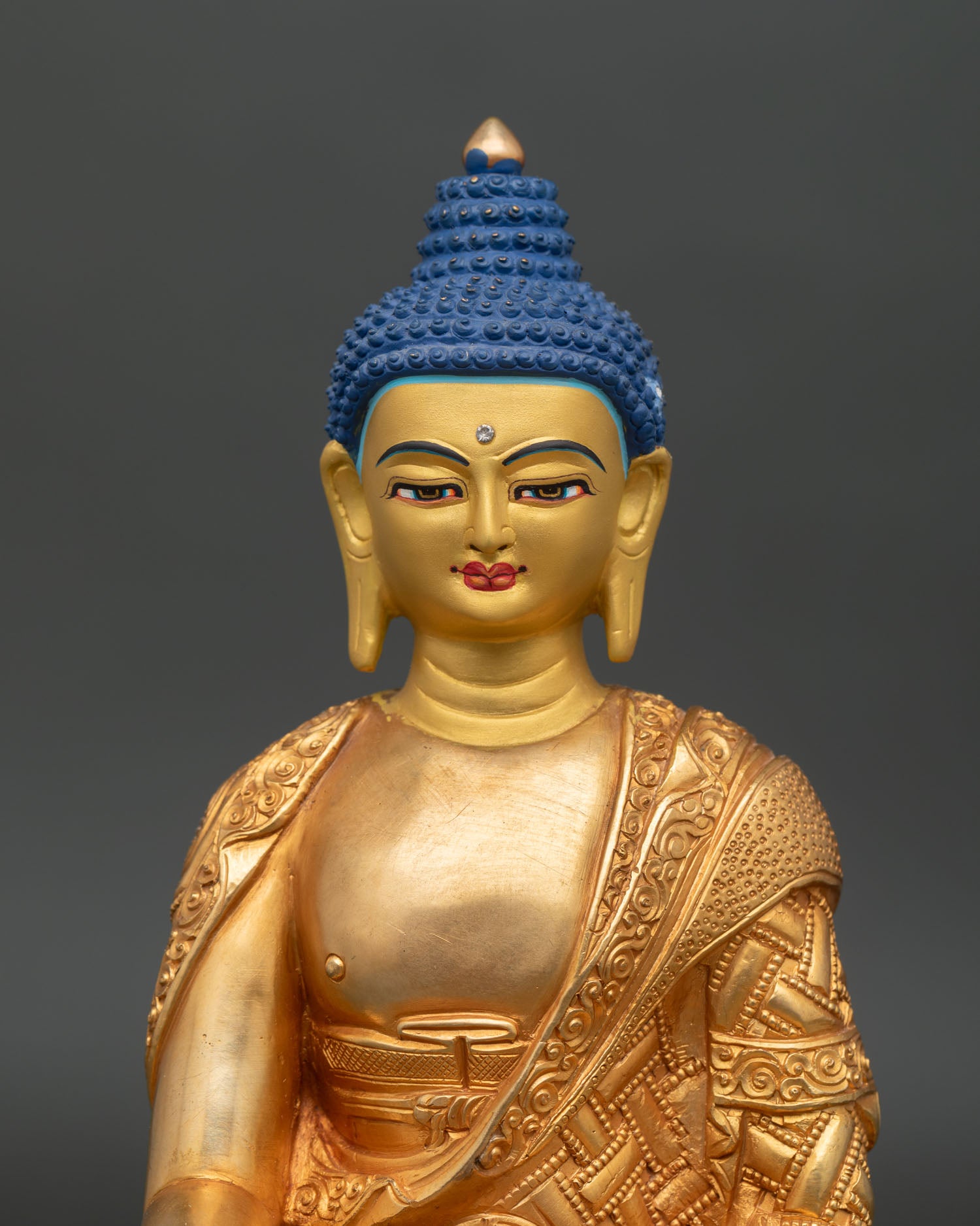 Close up of Shakyamuni Buddha statue showing serene gold painted face and intricate details