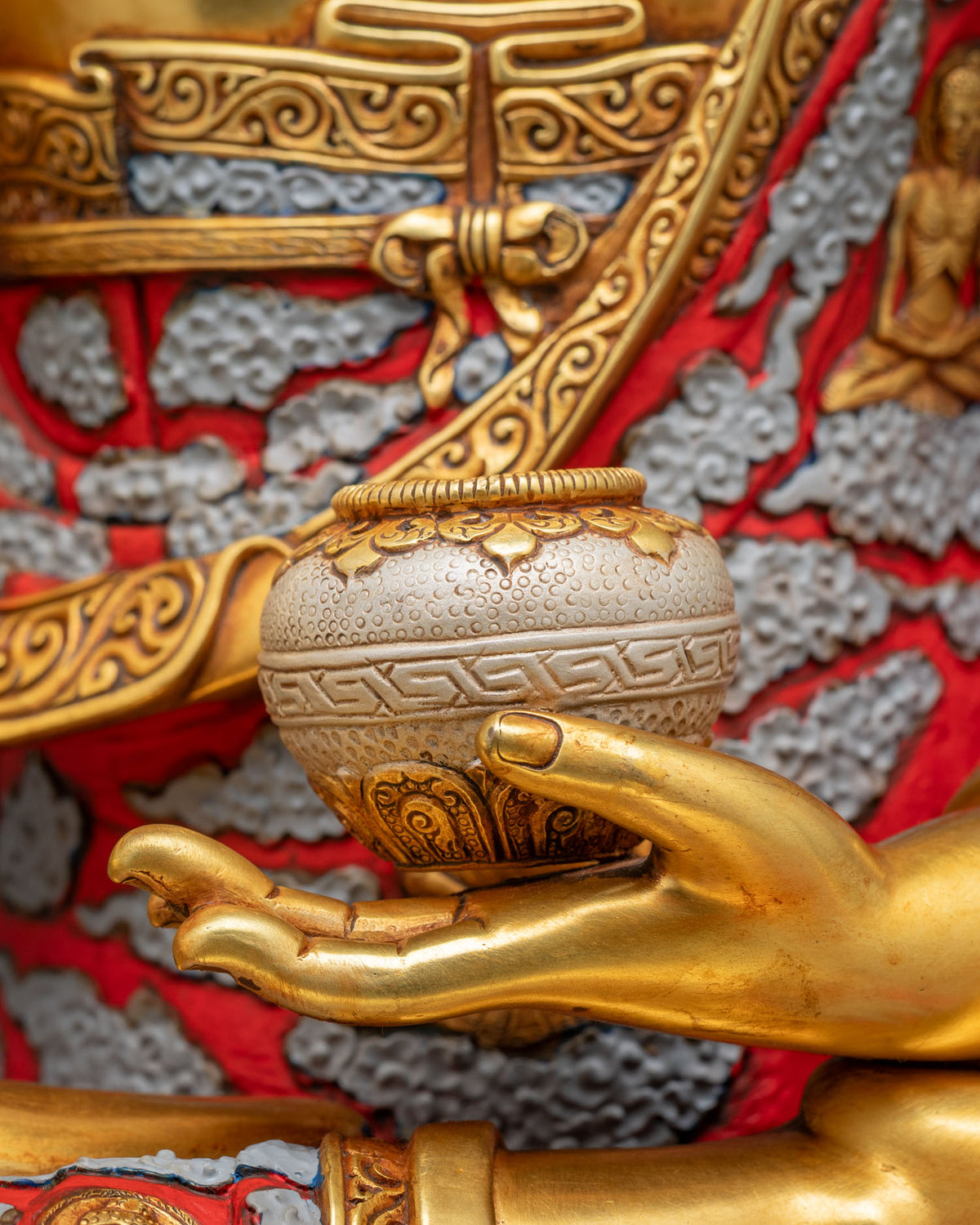 Close-up of Shakyamuni Buddha statue’s left hand holding a patra bowl with fine engraved detail