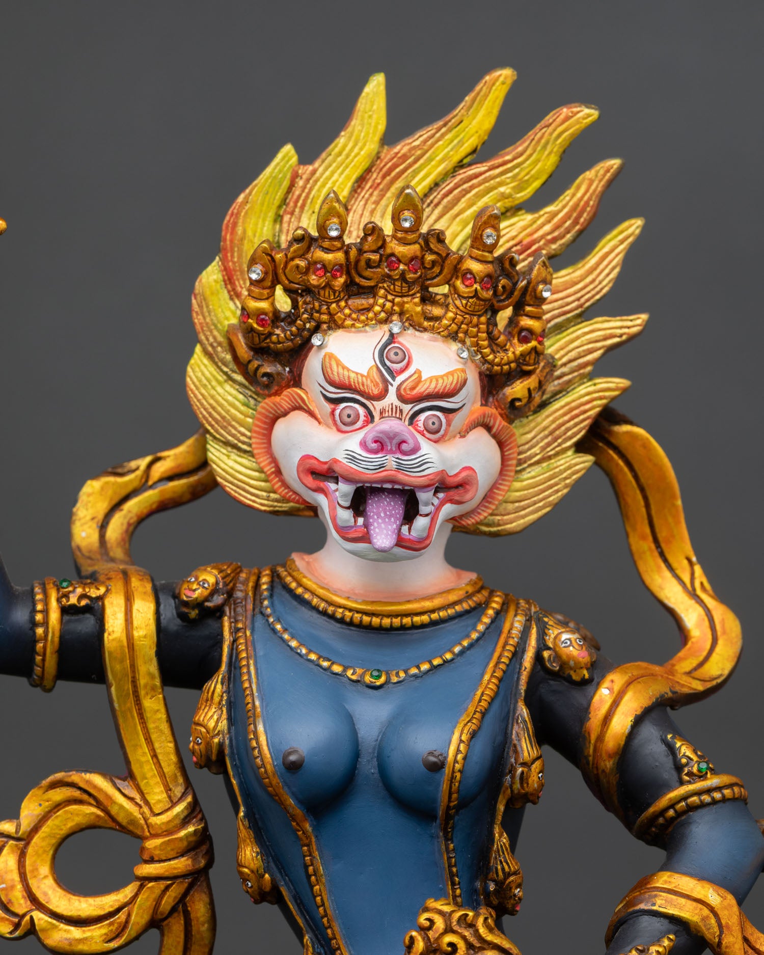 close-up of simhamukha dakini statue with gold-gilded ornaments and fierce posture