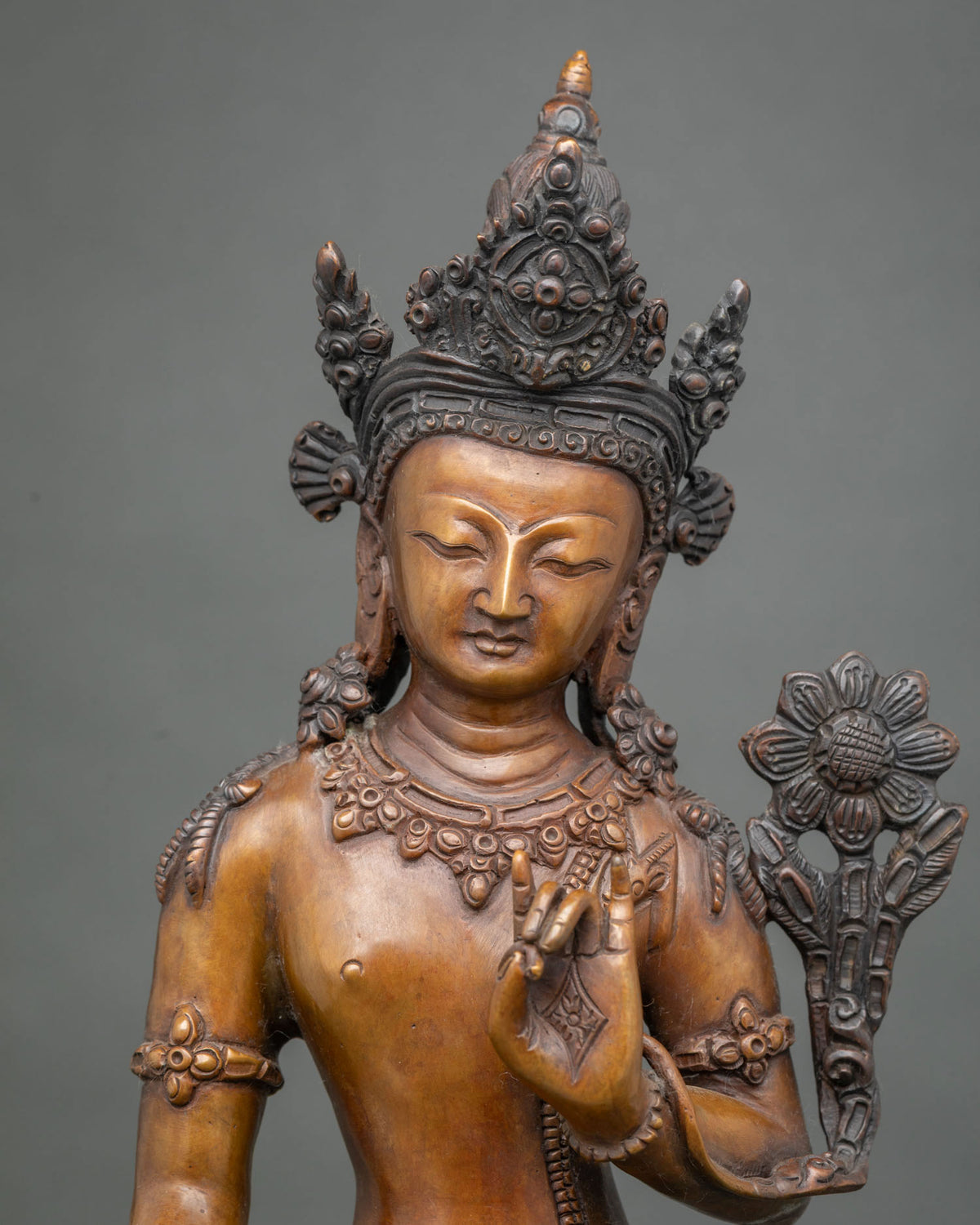 Close up of standing Avalokiteshvara statue with Utpala flower and jeweled necklace, oxidized copper