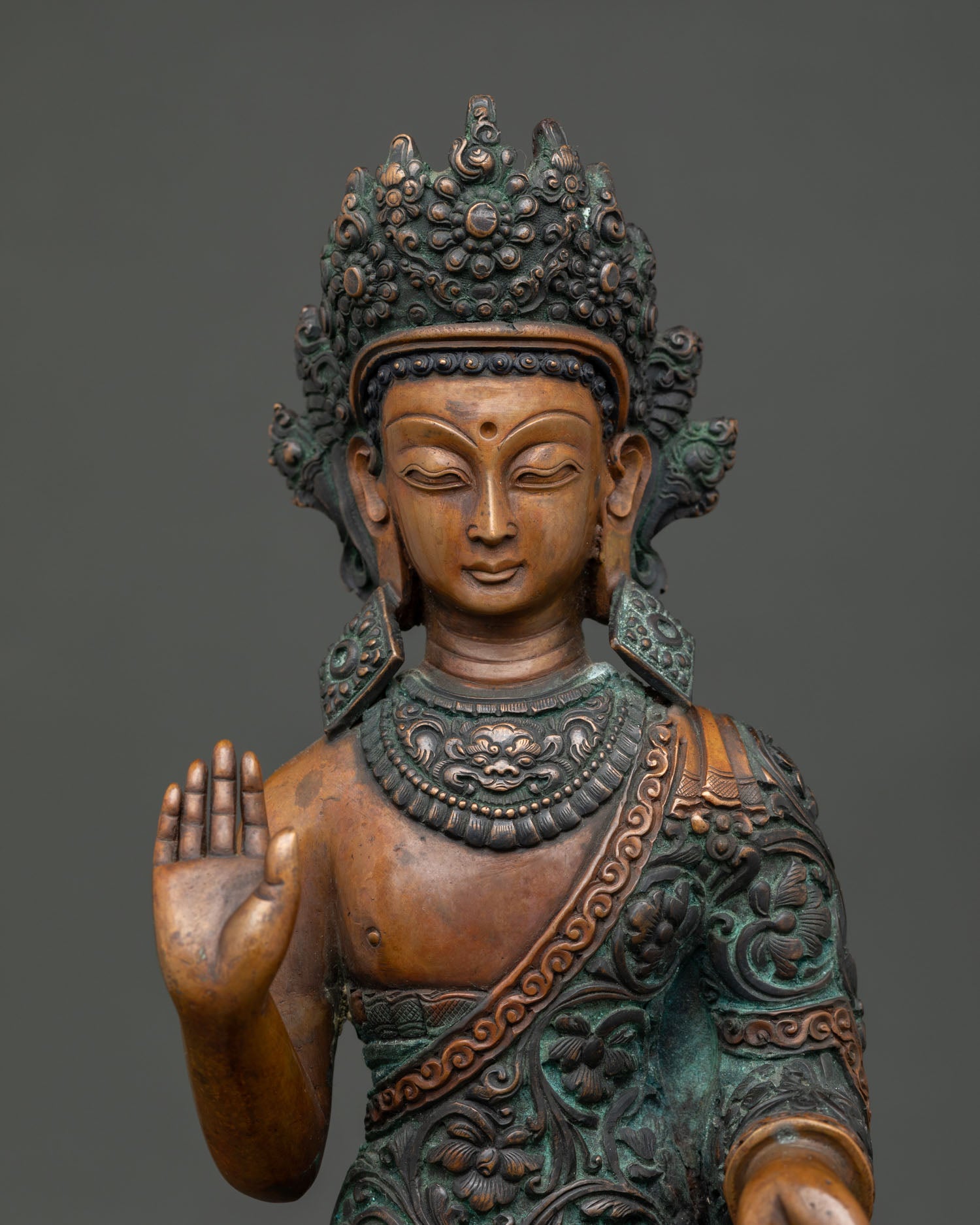 close up of standing dipankara buddha statue with handcrafted oxidized copper details